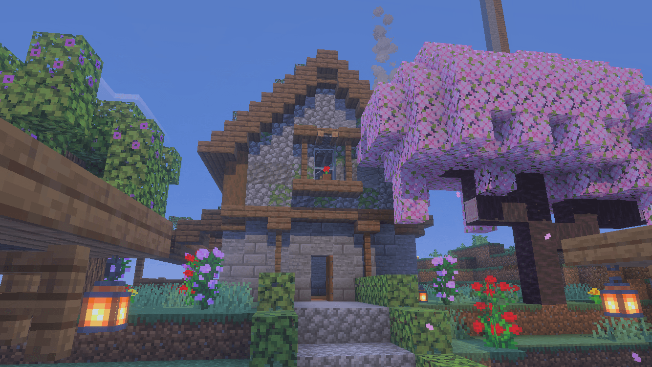 Large medieval stone house with a pink cherry blossom tree