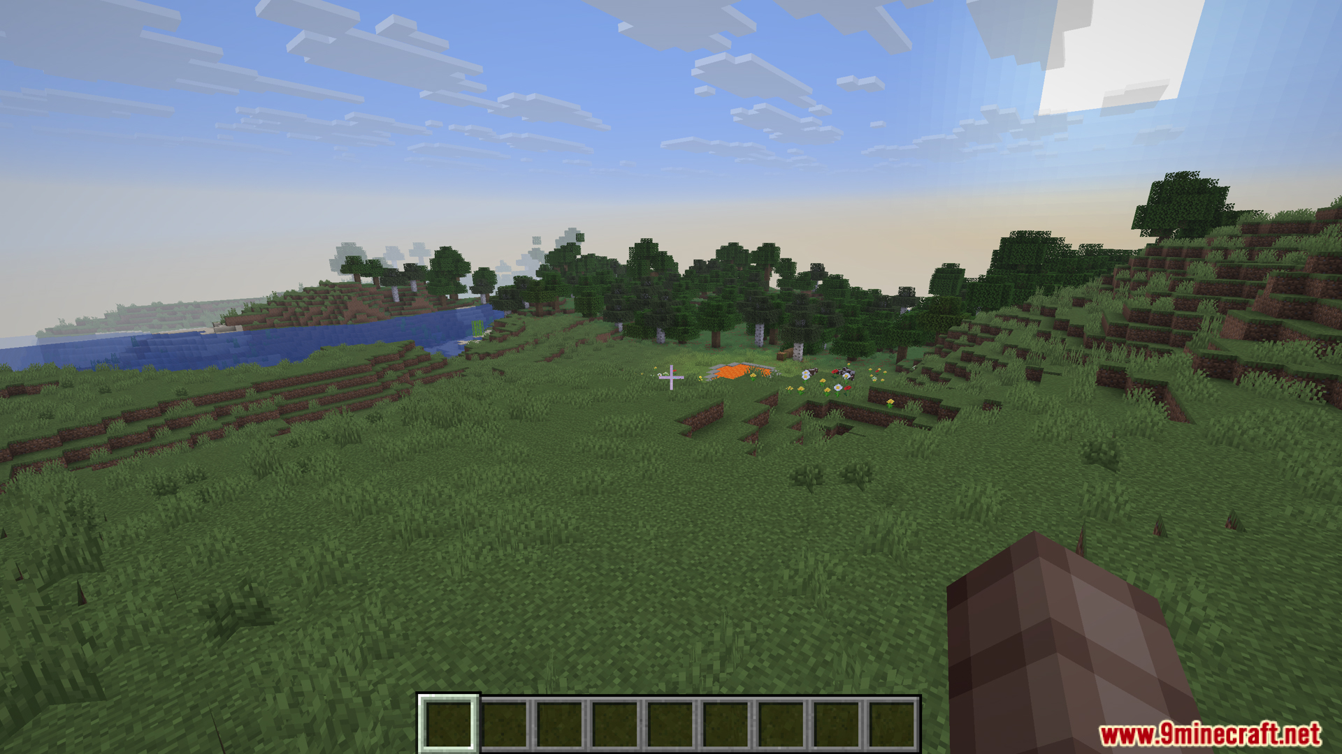 Player exploring a grassy plains biome with trees and a lake