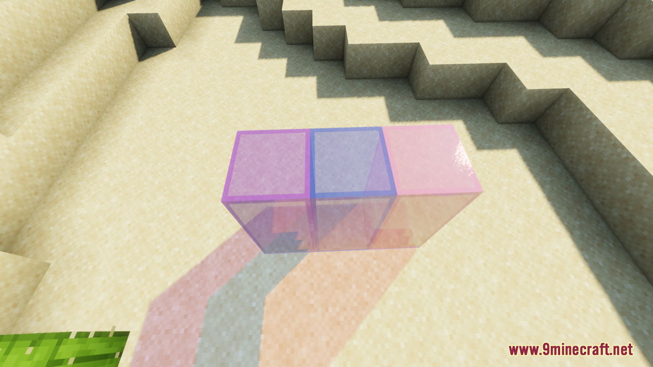 Three colorful tinted glass blocks lying on the sand