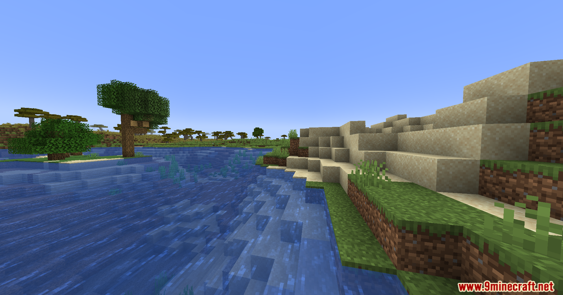 View of a sandy riverbank and savanna biome in Minecraft