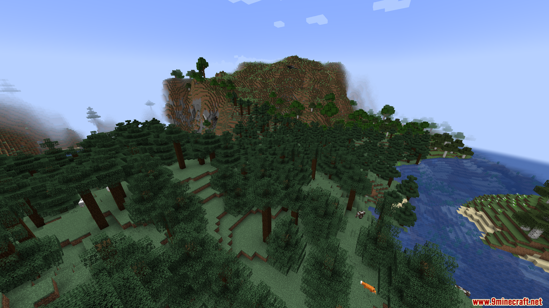 Aerial perspective of a forest biome near a river and large mountain