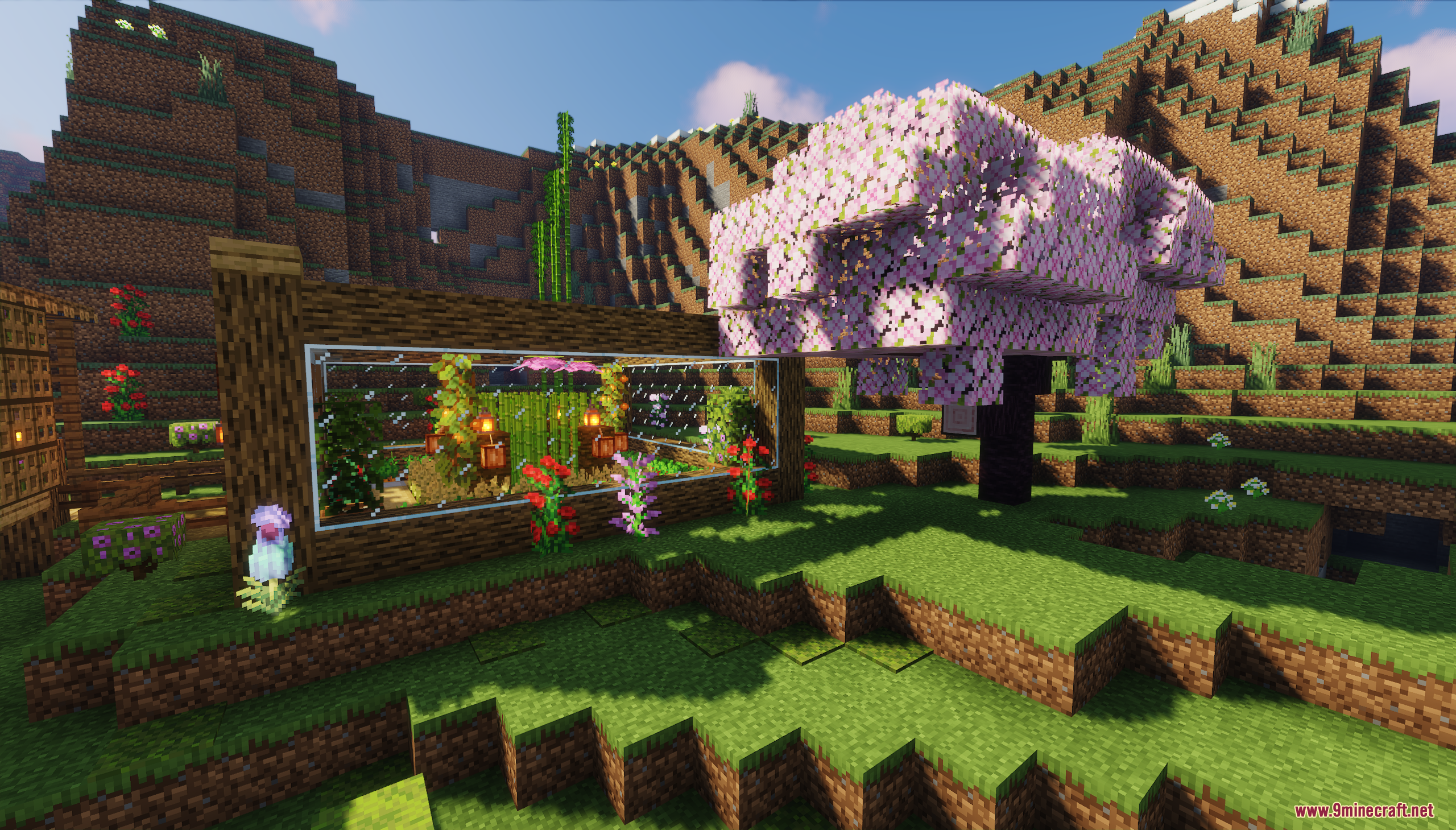 A glass greenhouse next to a pink blossom tree