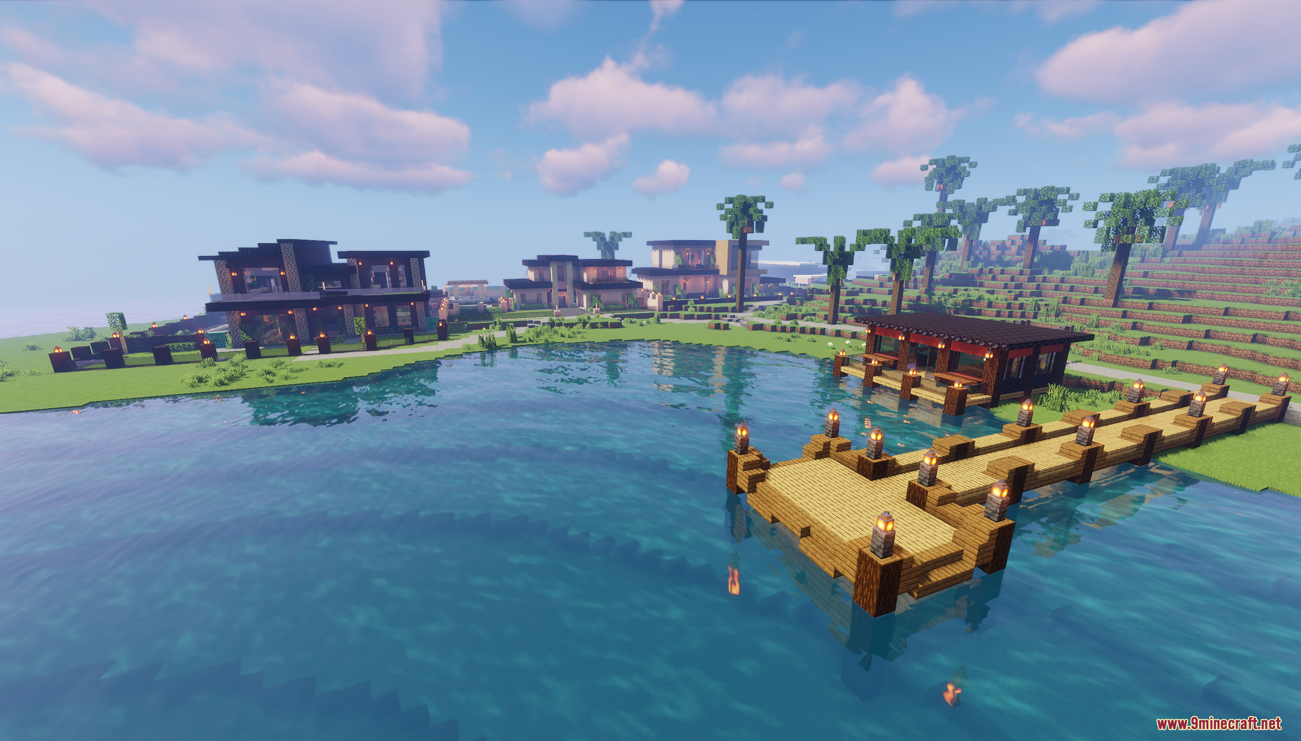 Wooden pier extending into water with modern houses in the background