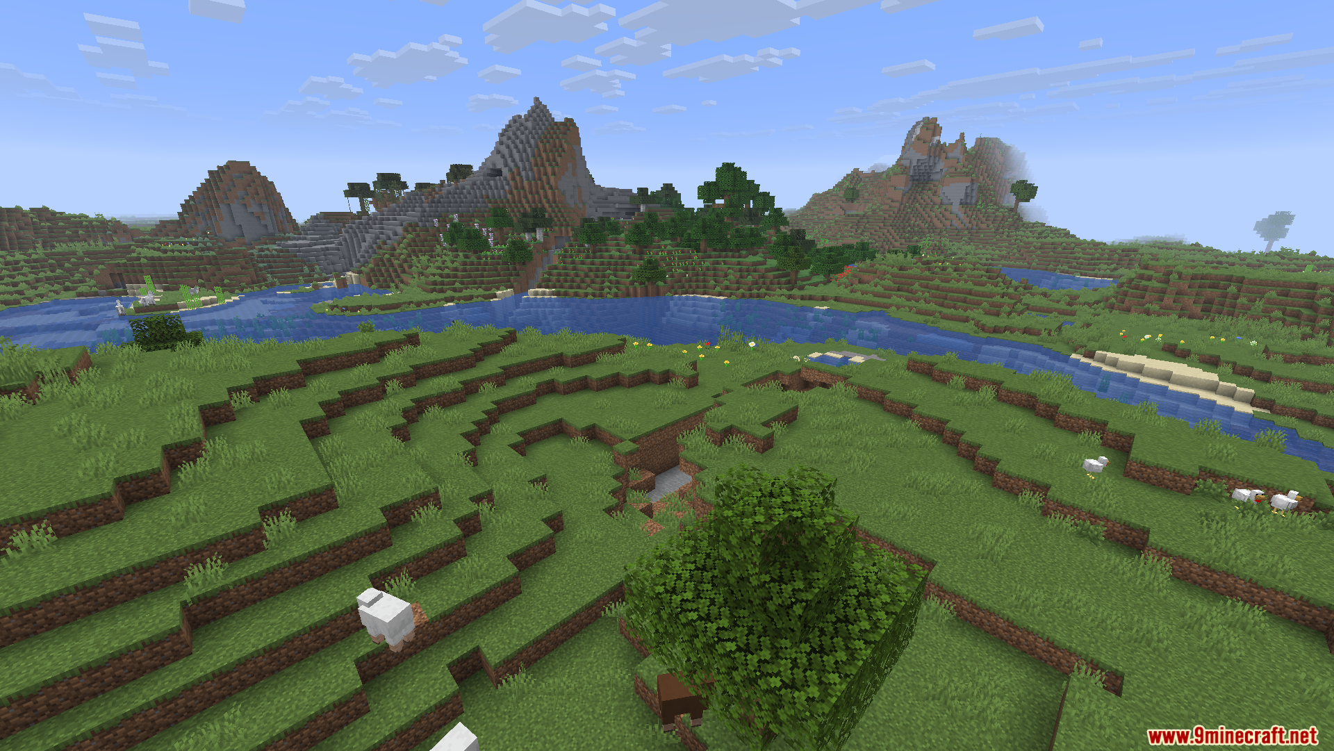 Wide landscape showing green plains a river and distant mountains