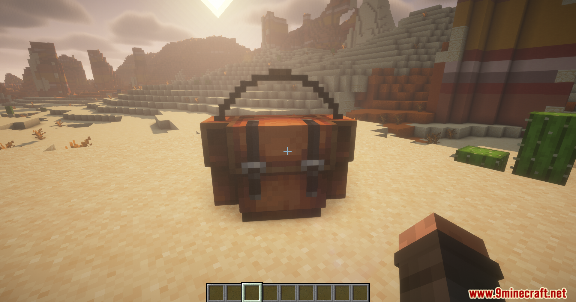 A large backpack placed on the sandy ground