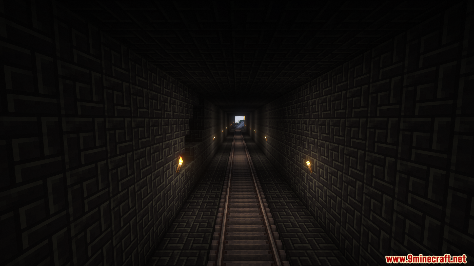 Dark stone brick tunnel with train tracks lit by wall torches