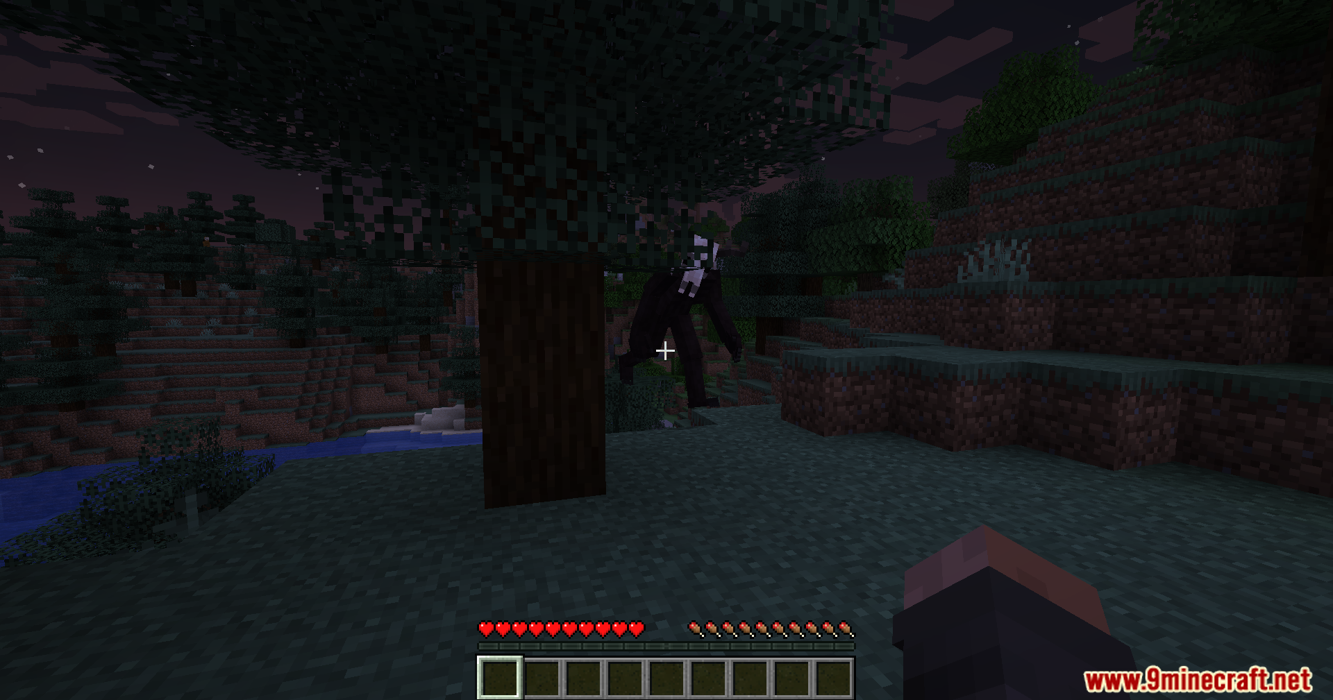 The Wendigo monster appears from behind a large tree