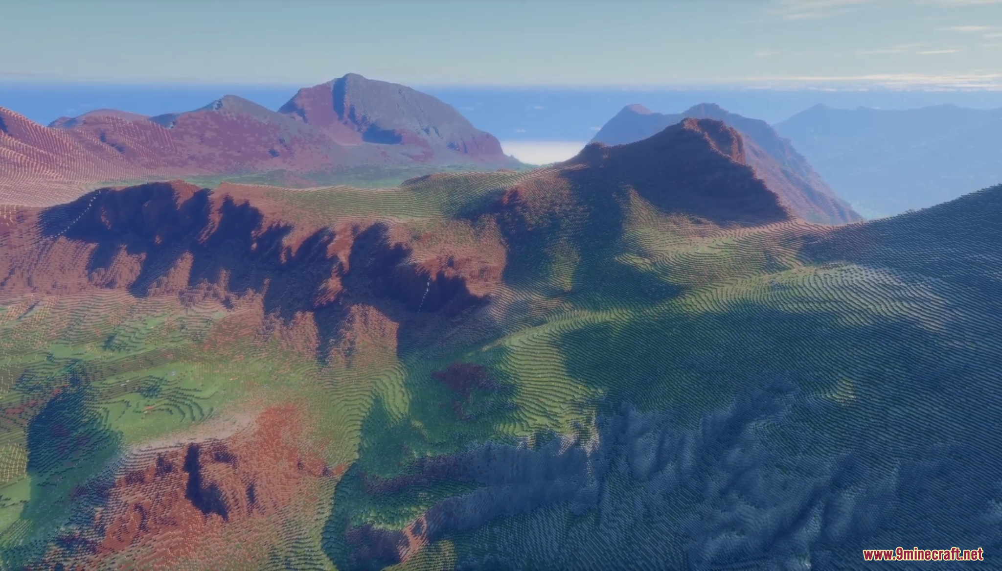 Aerial view of green alpine valleys and rugged reddish mountain peaks