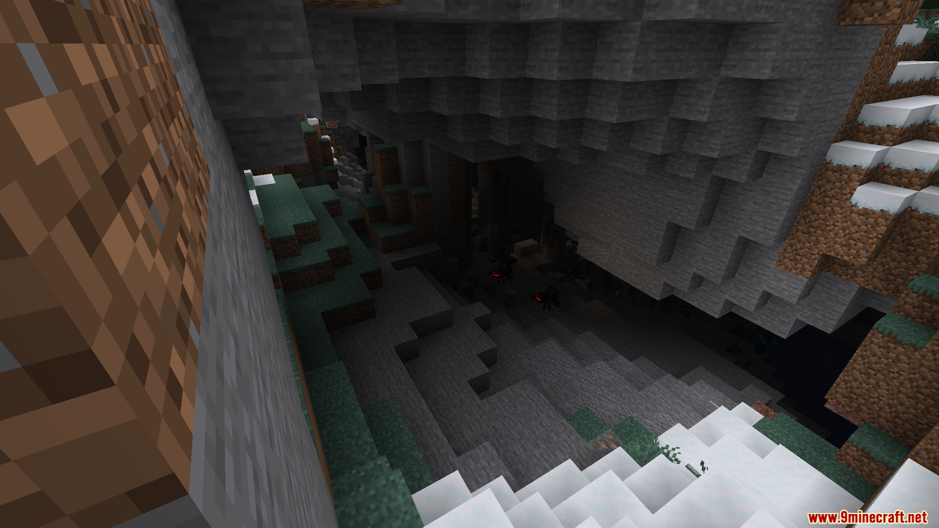A dark cave entrance in a snowy, rocky mountain