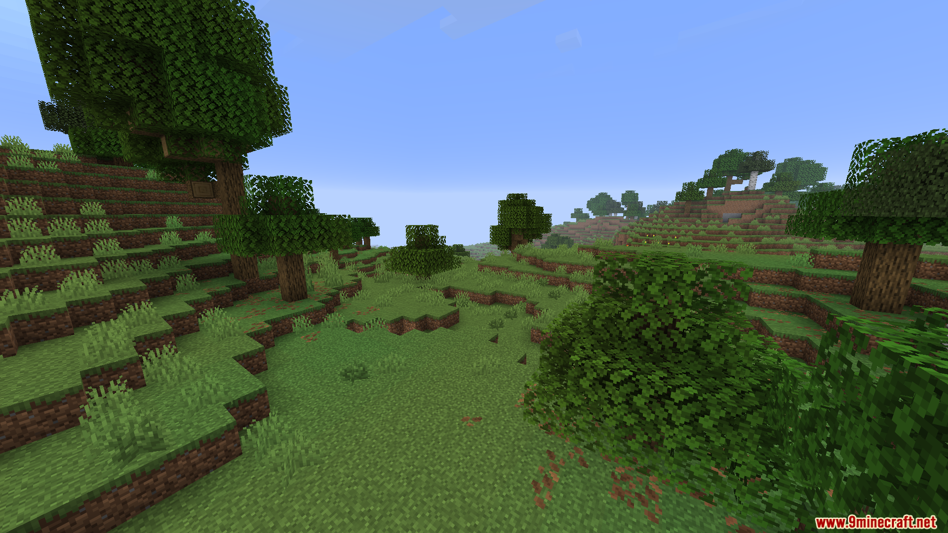 WorldWeaver Neoforge Mod Screenshot 7 Lush green valley landscape featuring scattered oak trees and bushes