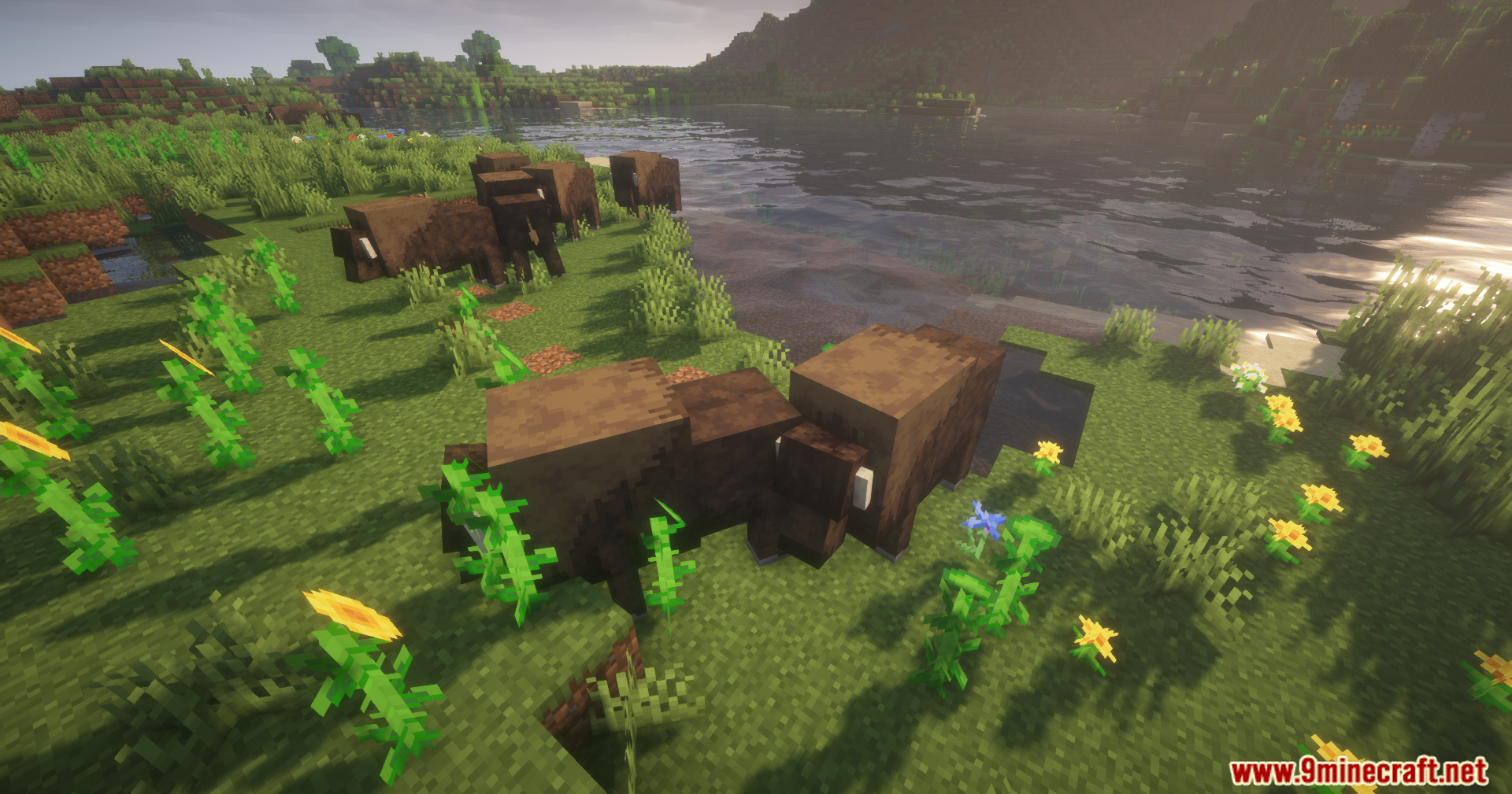 Alex's Mobs Unofficial Port Mod Screenshot 5 Several brown bison mobs grazing among flowers near a river in the game