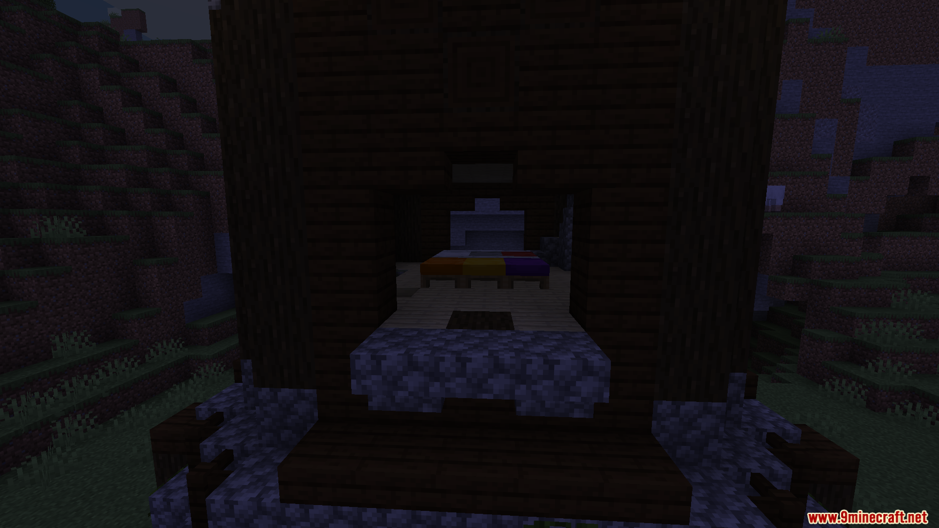 A multi-colored bed inside a small wooden shelter