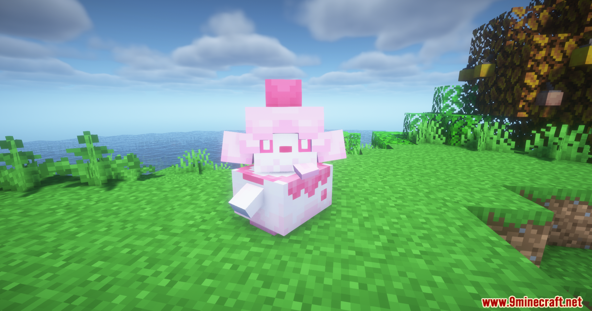 A pink and white Swirlix Pokemon sitting on grass near the ocean