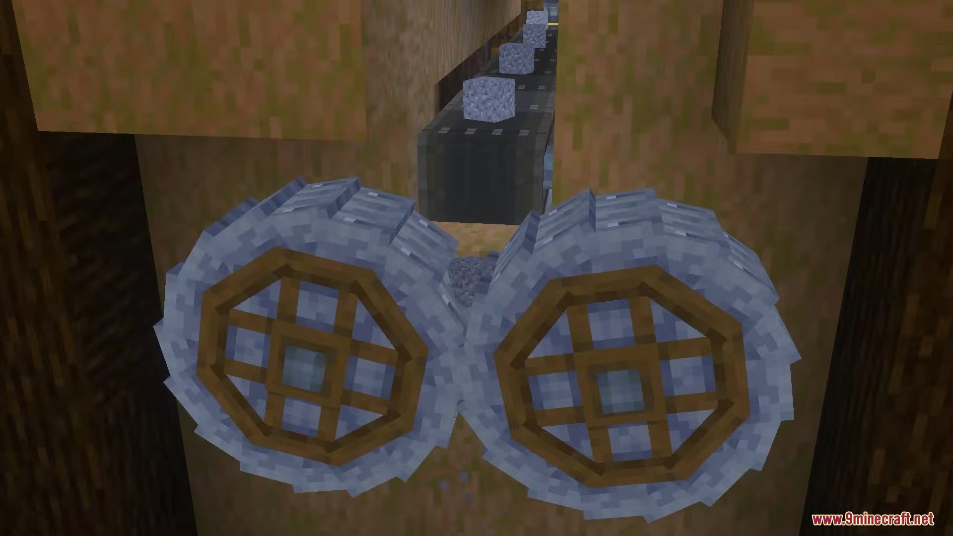 Two large crushing wheels processing cobblestone dropped from a mechanical belt above