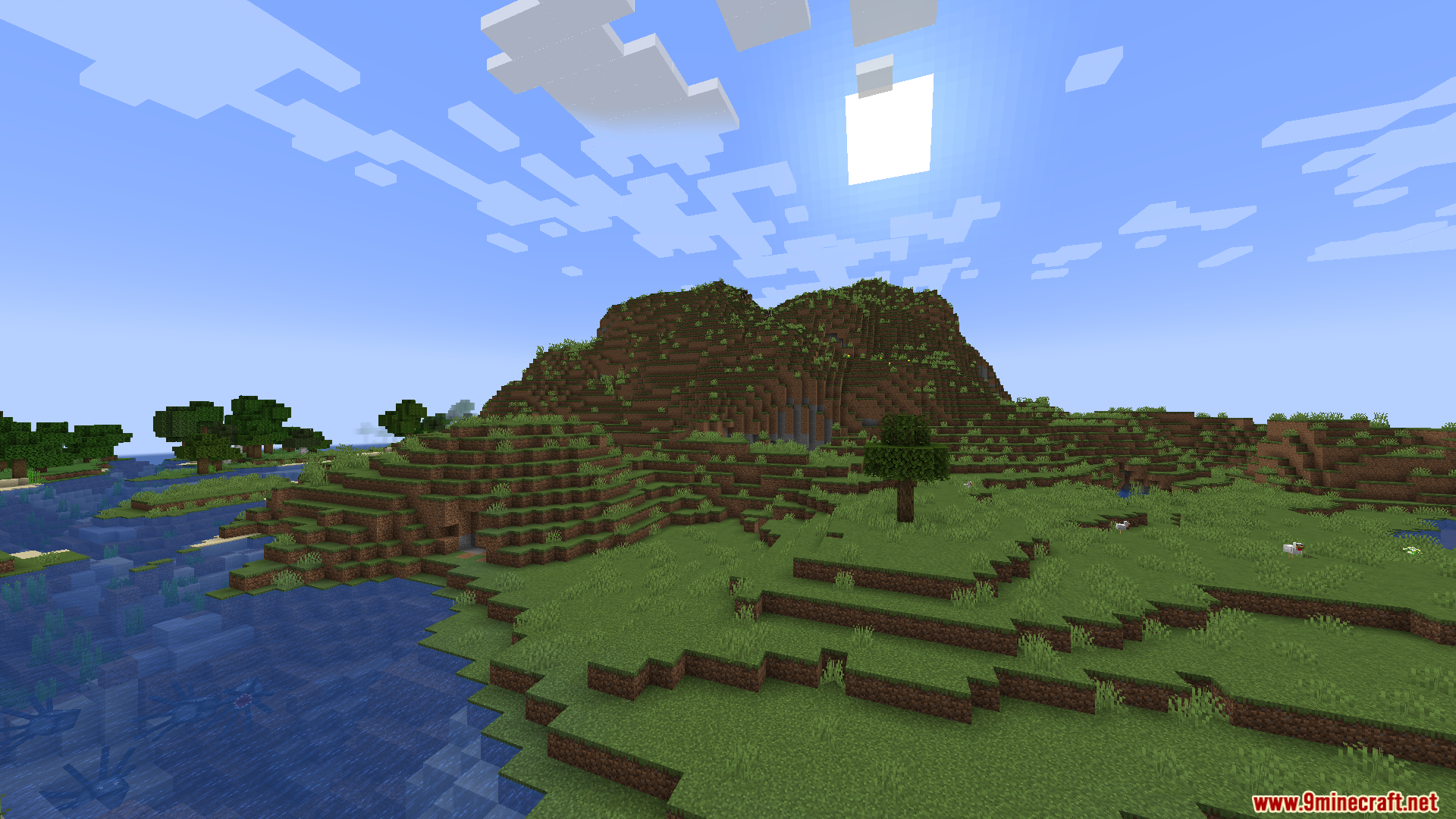 A large grassy mountain stands under the bright sun