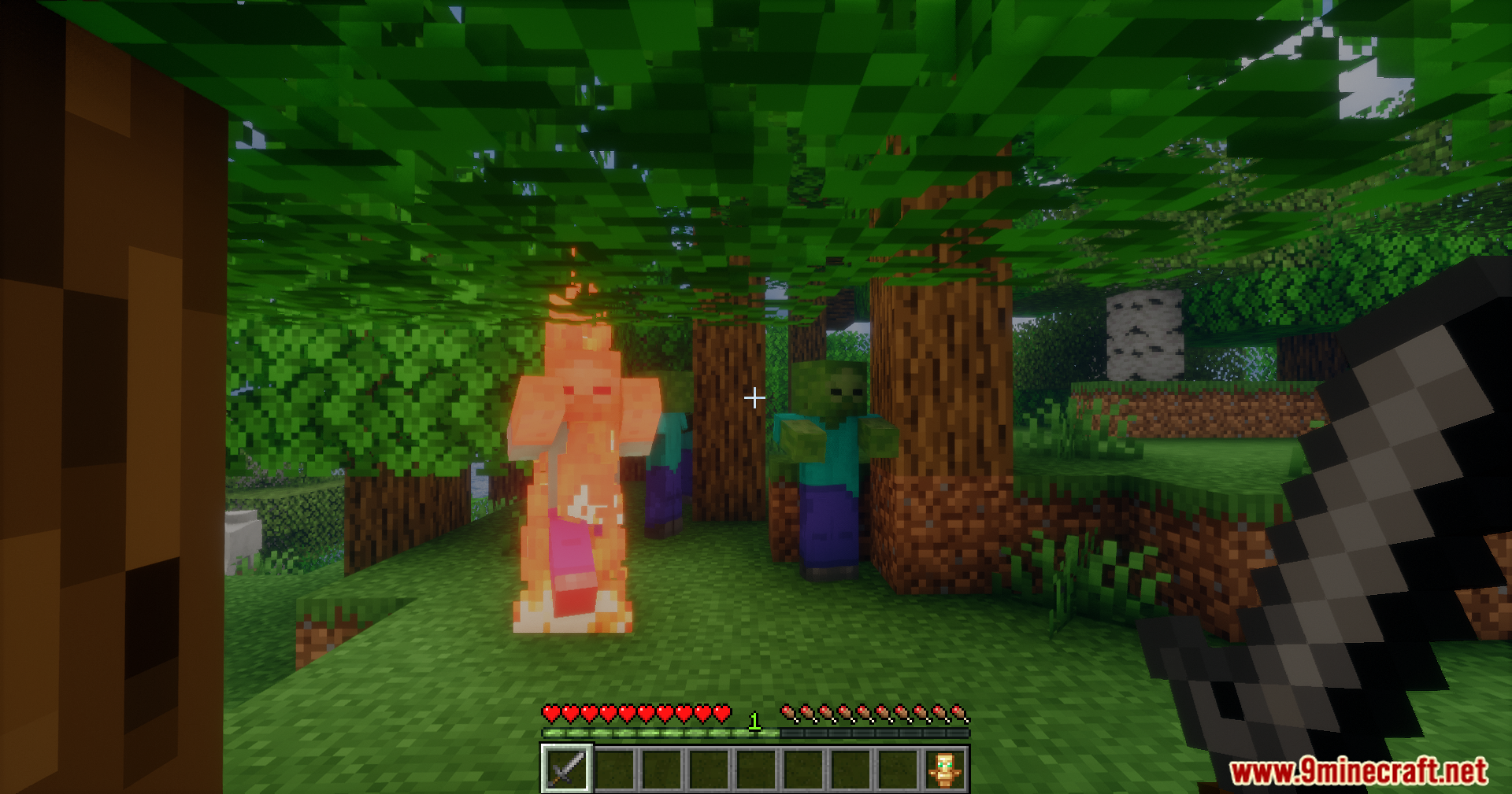 Player fighting burning zombies while holding a sword and offhand totem