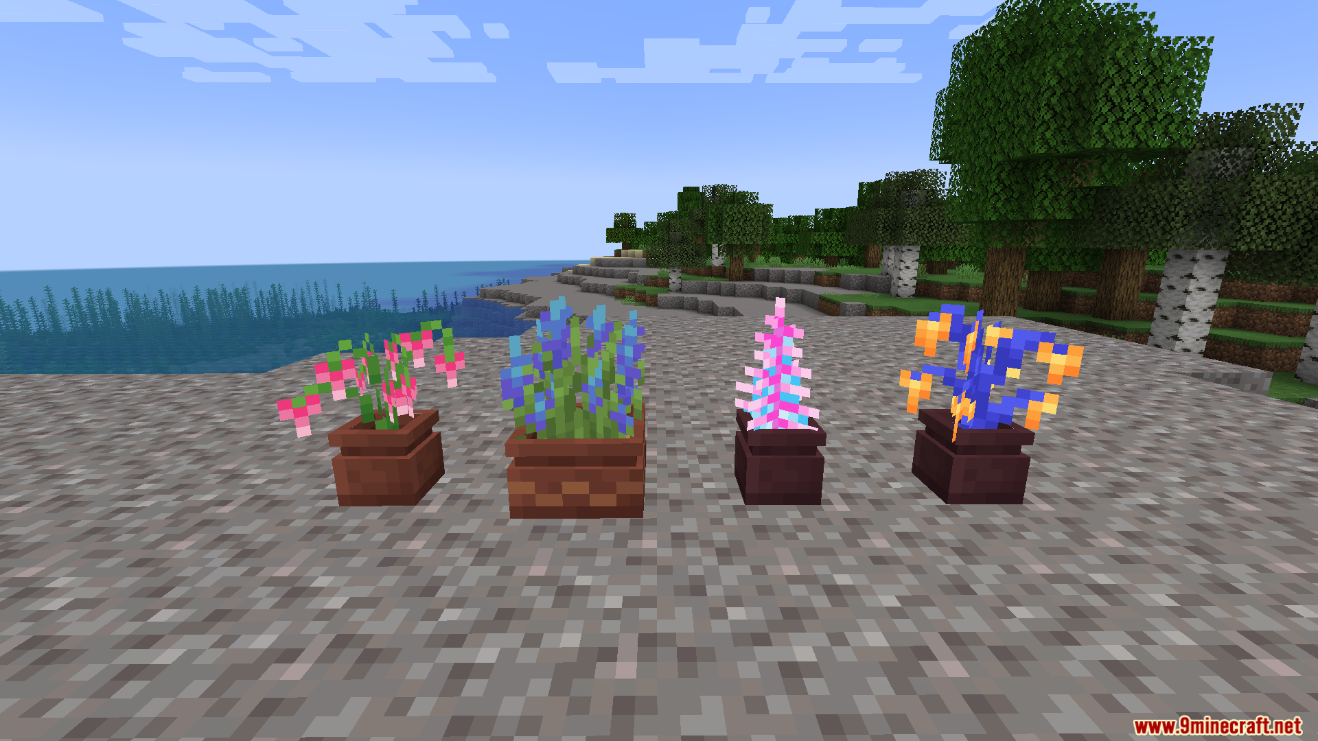 Four colorful modded plants placed in custom flower pots on a gravel beach
