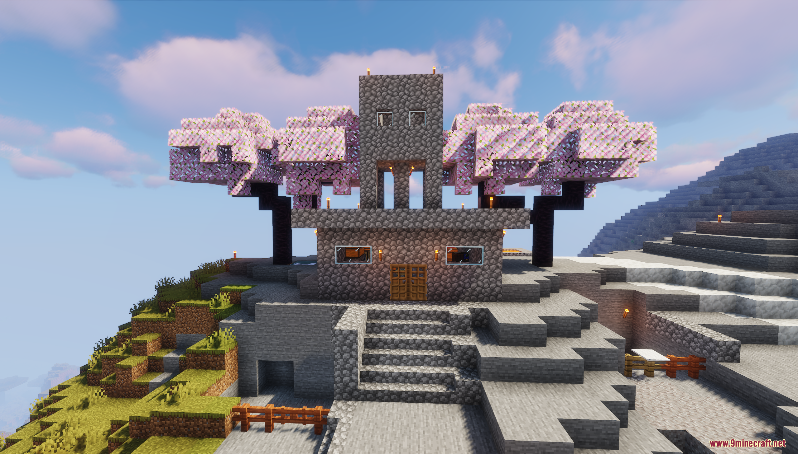 A stone house nestled between two large cherry blossom trees