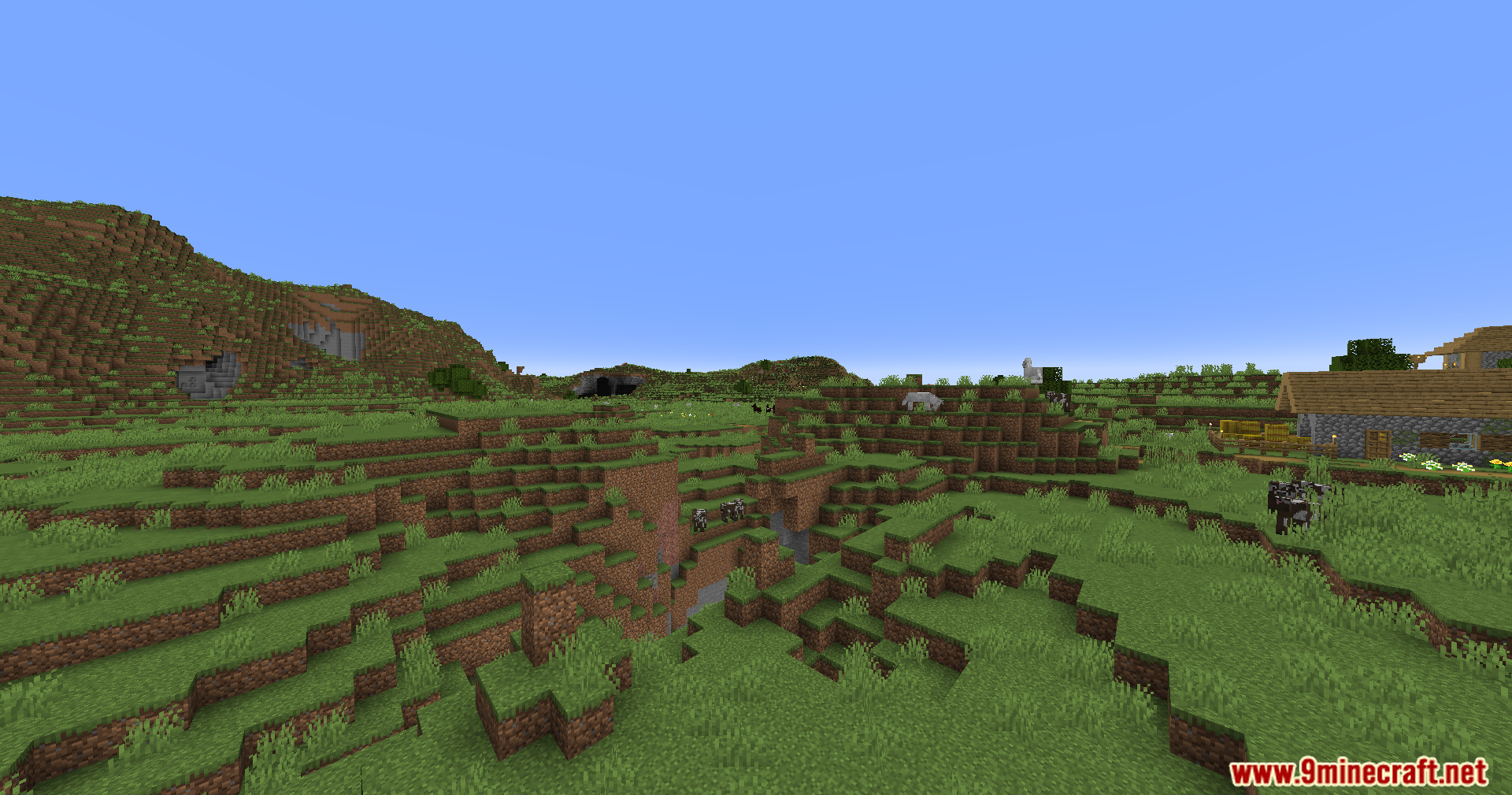 Noisiumed Mod Screenshot 7 A wide view of a grassy landscape with a village and a ravine