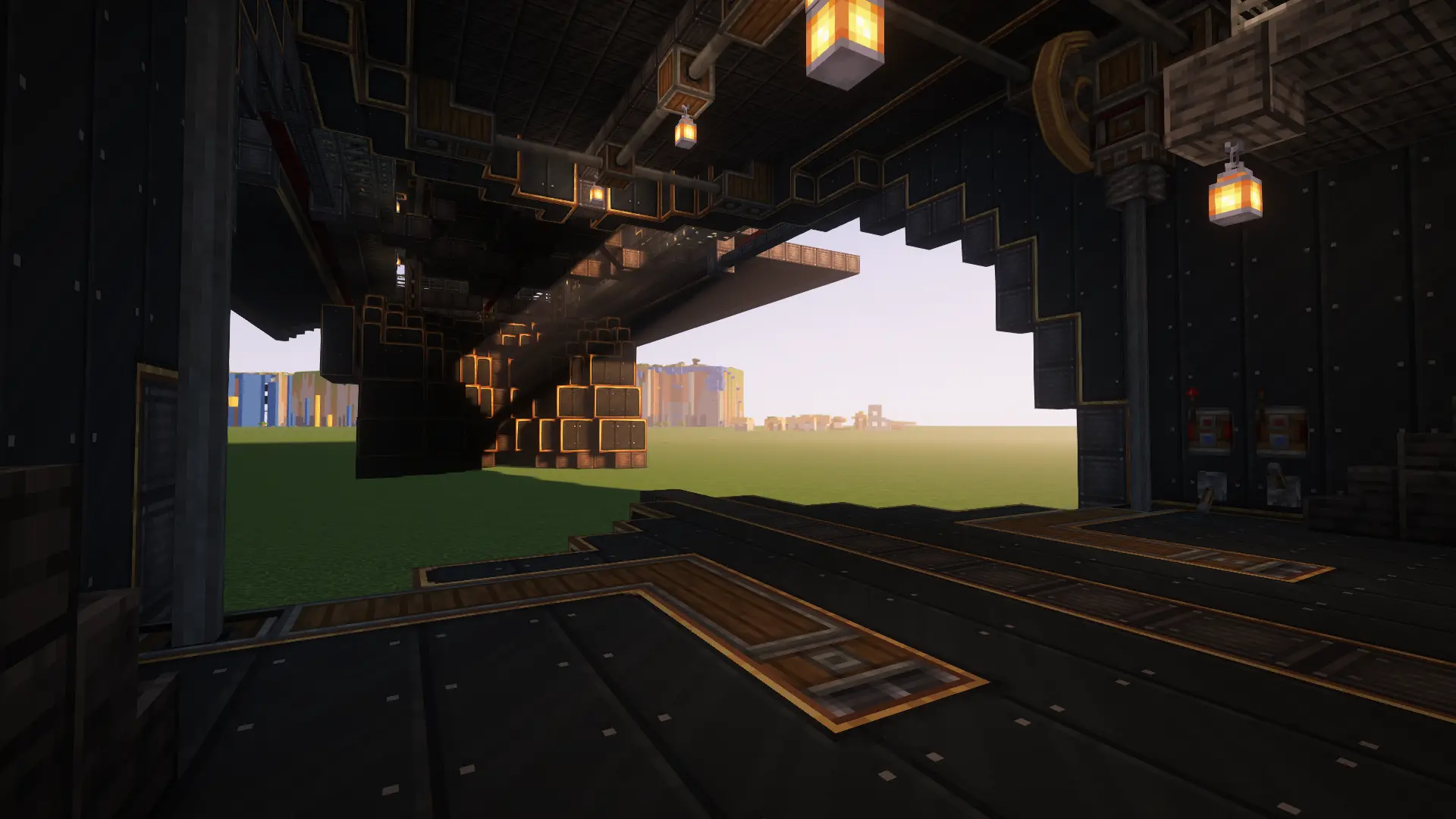 Inside a dark industrial airship hangar looking out onto a flat green field