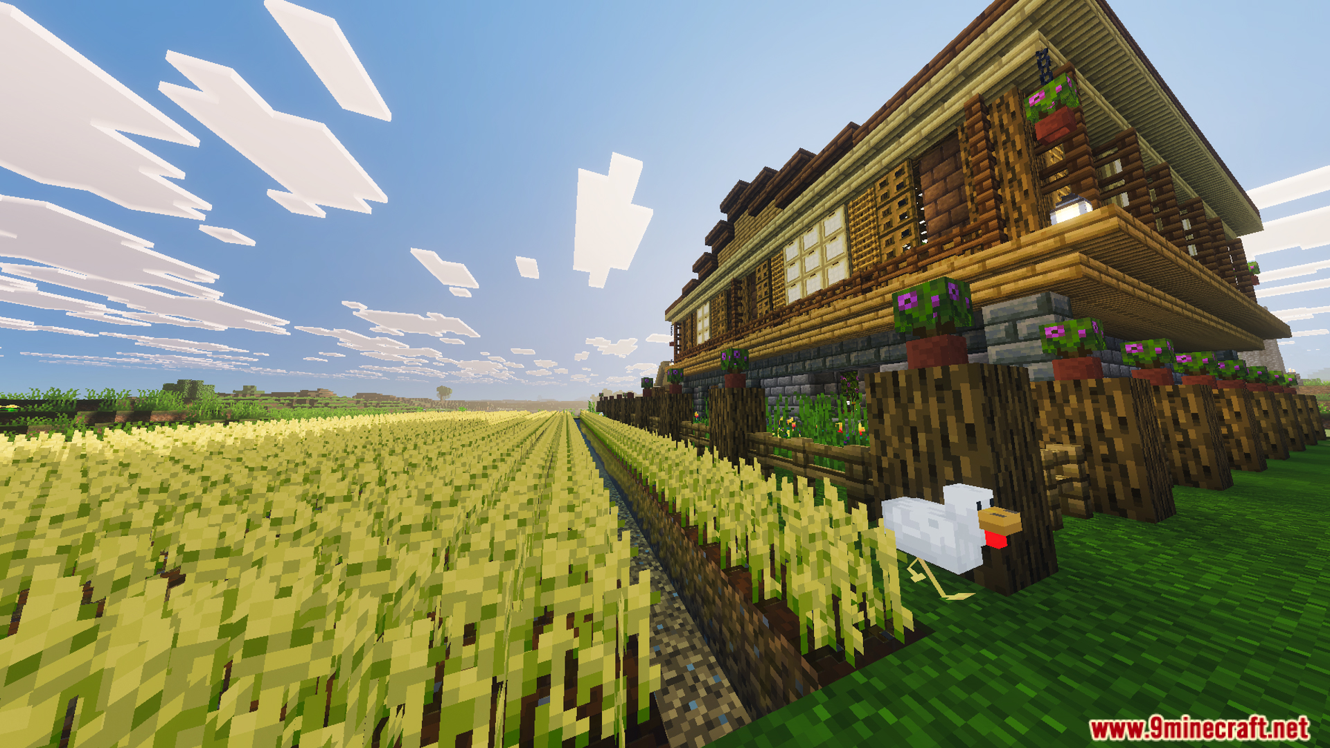 Large two story wooden house with a stone foundation and a wheat farm