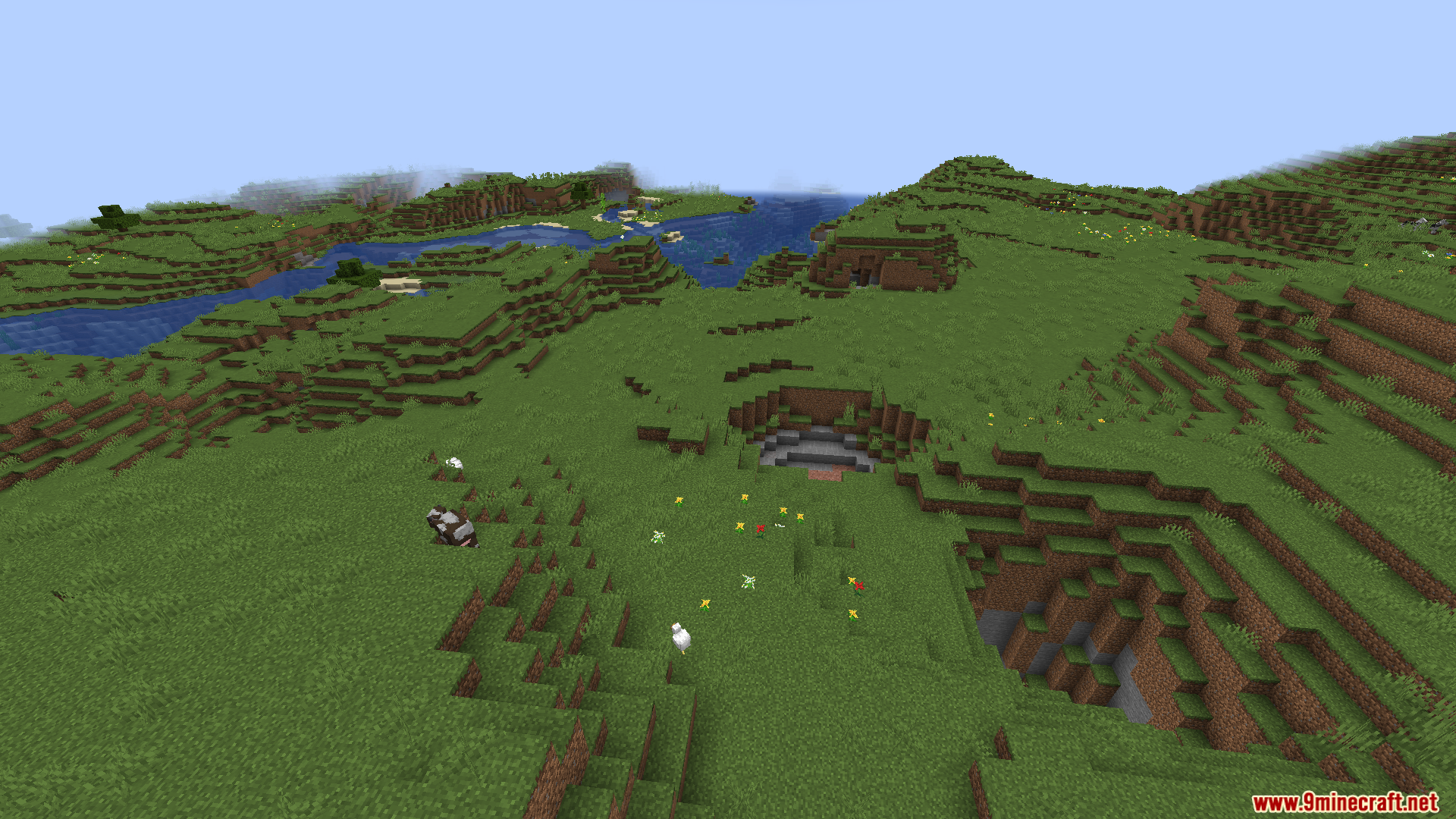 A wide landscape featuring a river and cows in a grassy plains biome