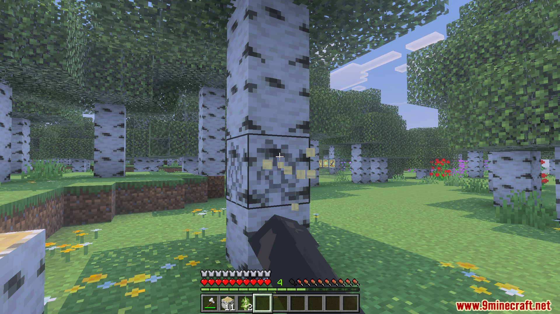 A player uses bare hands to break the bottom block of a birch tree