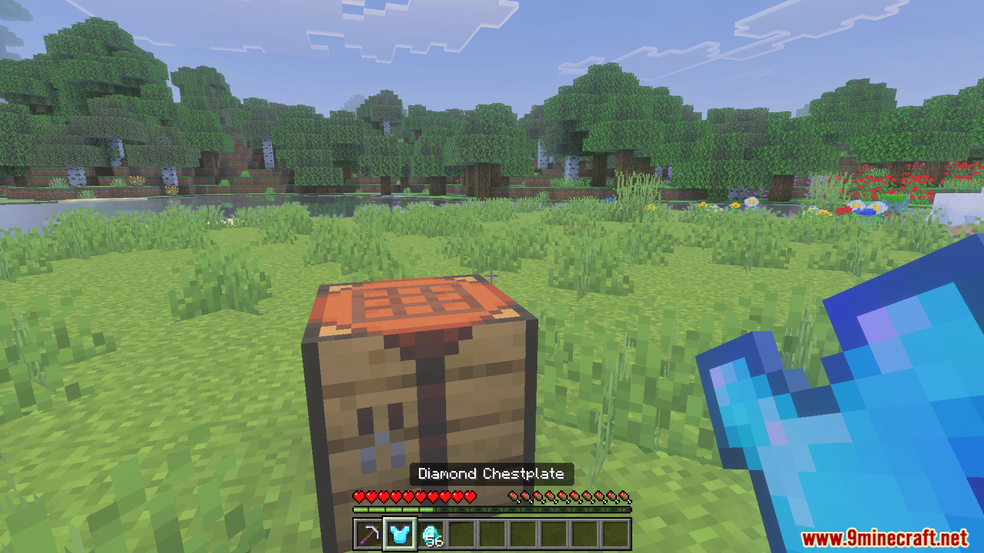 Minecraft player holding a diamond chestplate in front of a crafting table