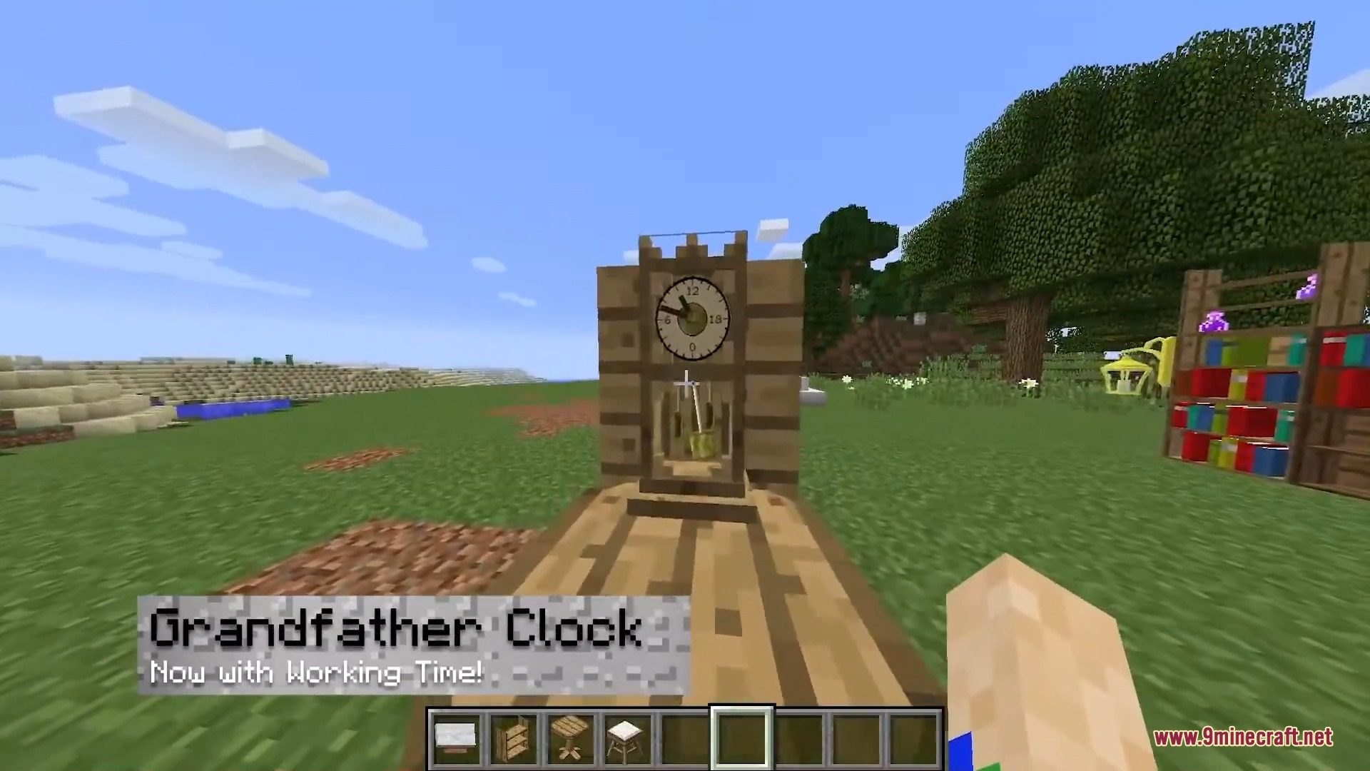 A wooden grandfather clock stands in a grassy field under a blue sky