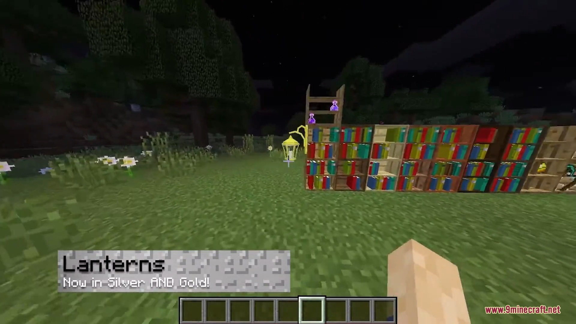 A gold lantern and colorful bookshelves are placed on grass at night
