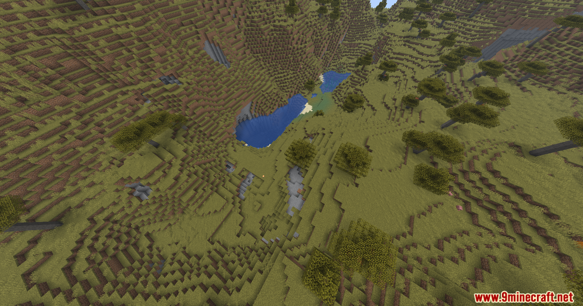 Aerial view of a savanna valley with a small lake and acacia trees