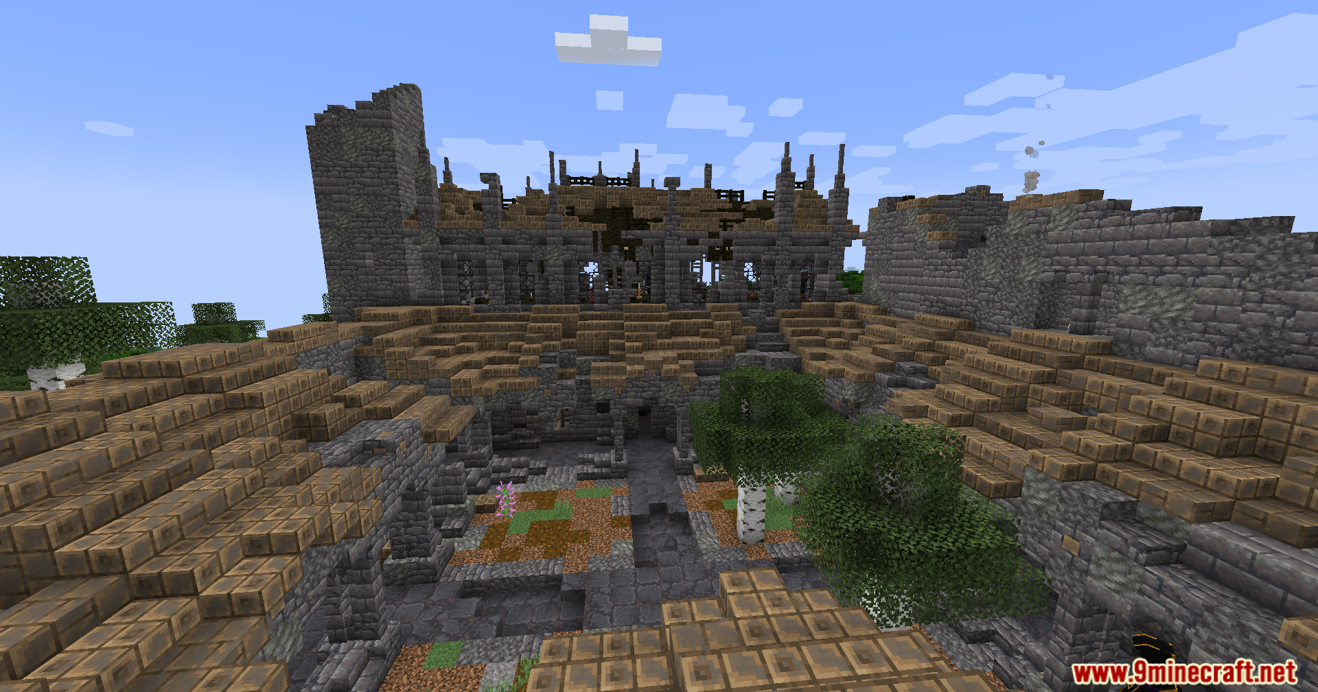 A large ruined stone structure with a tiered courtyard and trees