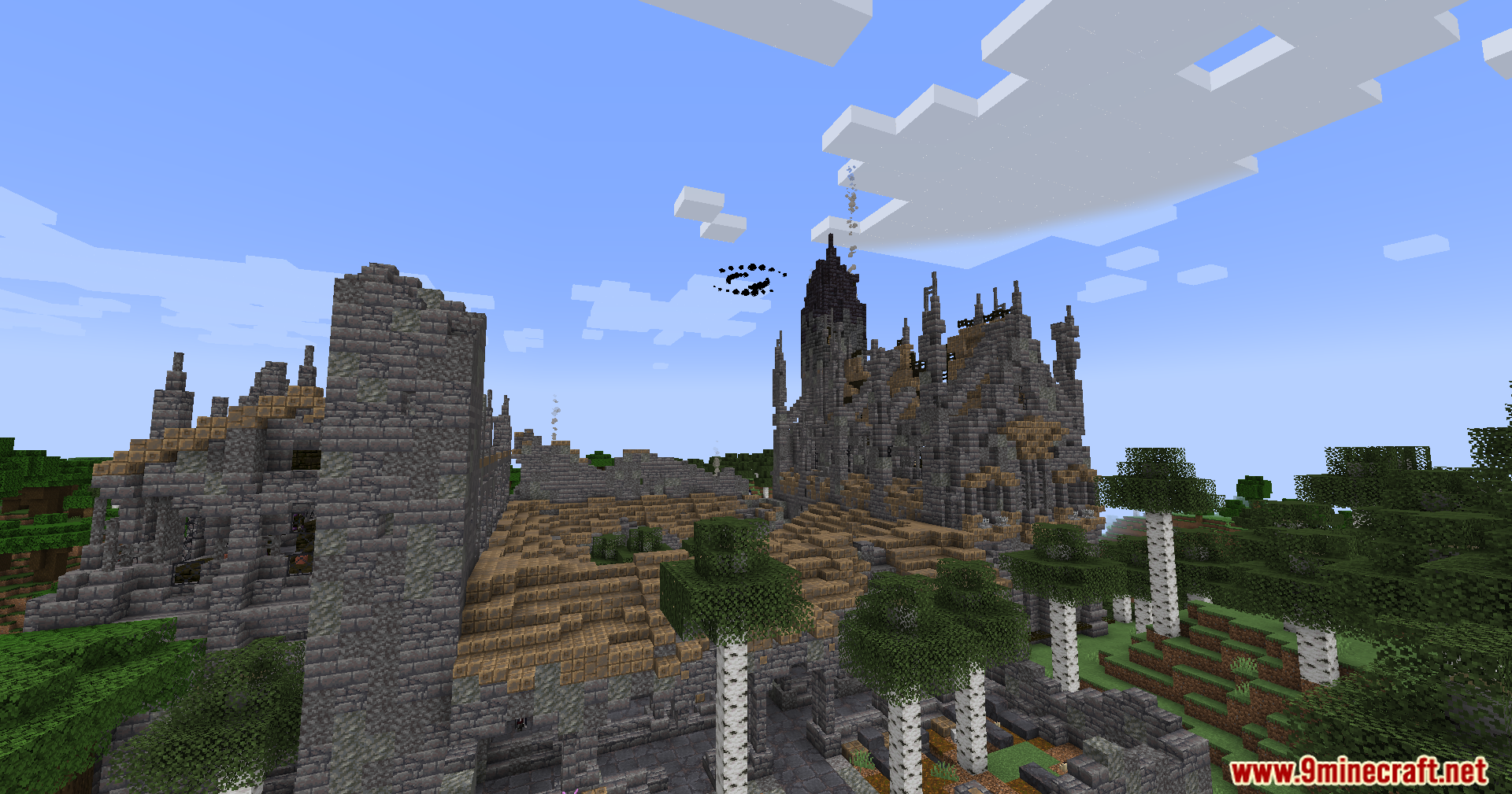 A tall ruined stone chapel with a dark spire and birch trees