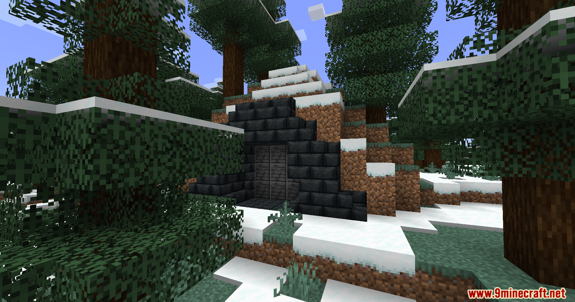 A small dark stone entrance built into a snowy hillside in the forest