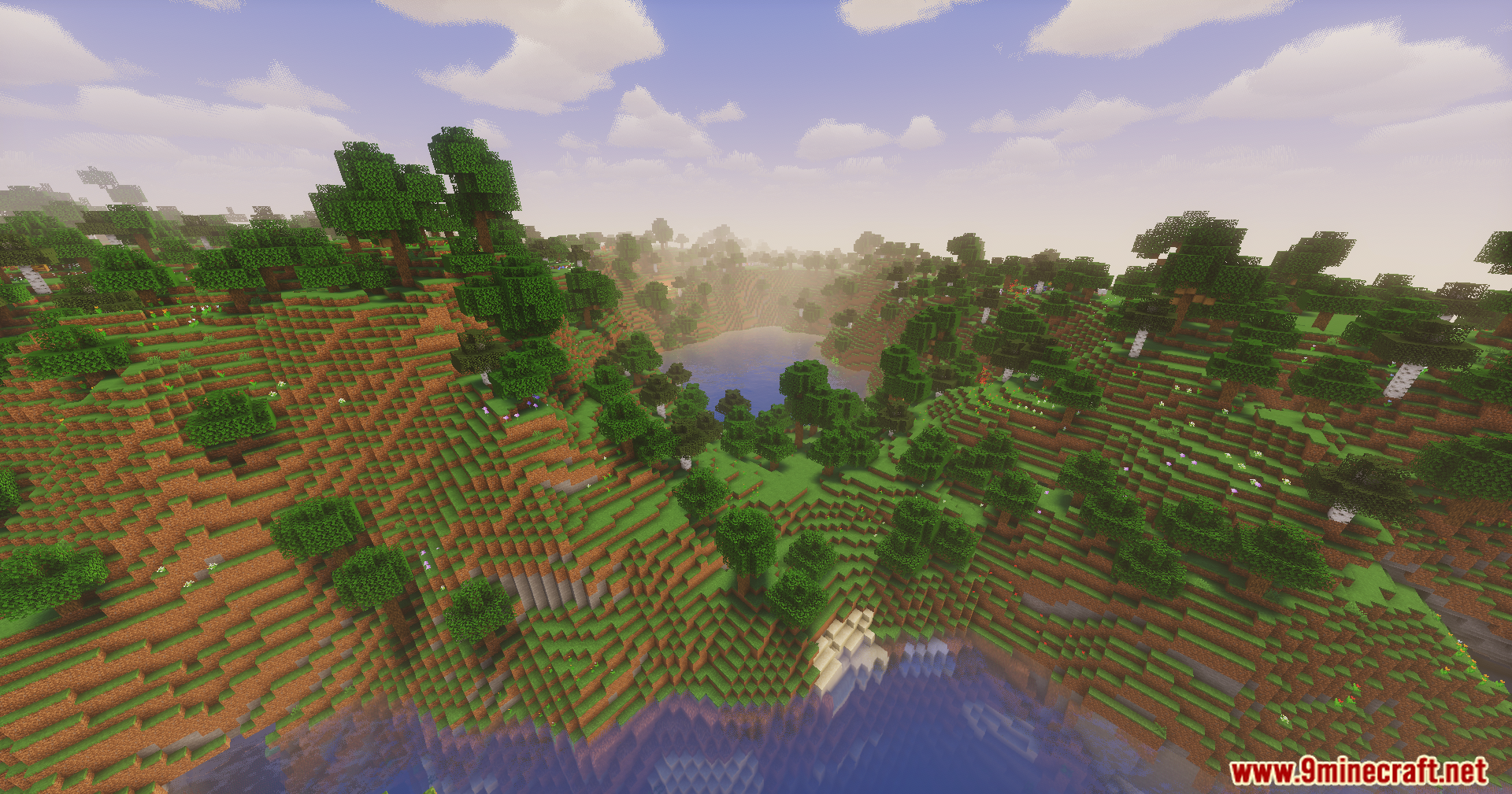 Lush green forest landscape with rolling hills and a calm blue lake