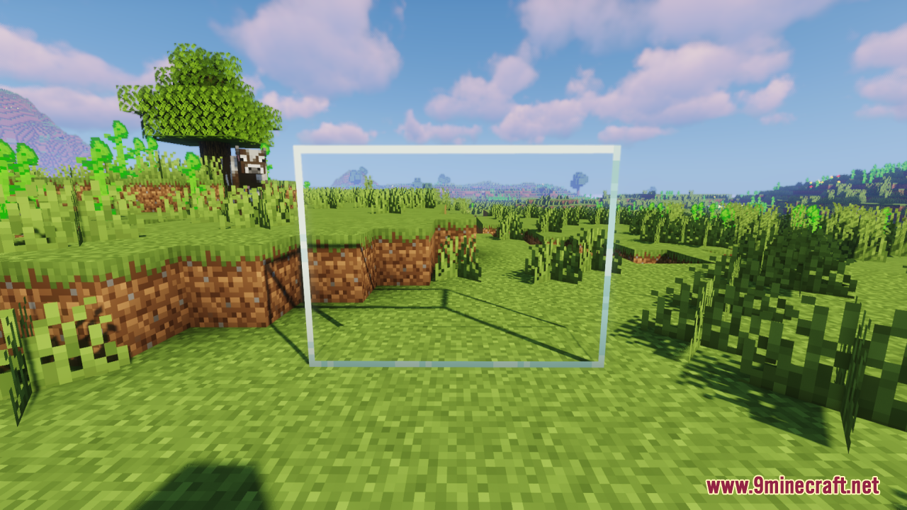 A clear glass pane stands in a grassy field under a blue sky