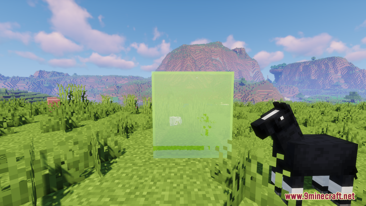 A clear green glass block placed on grass next to a black horse