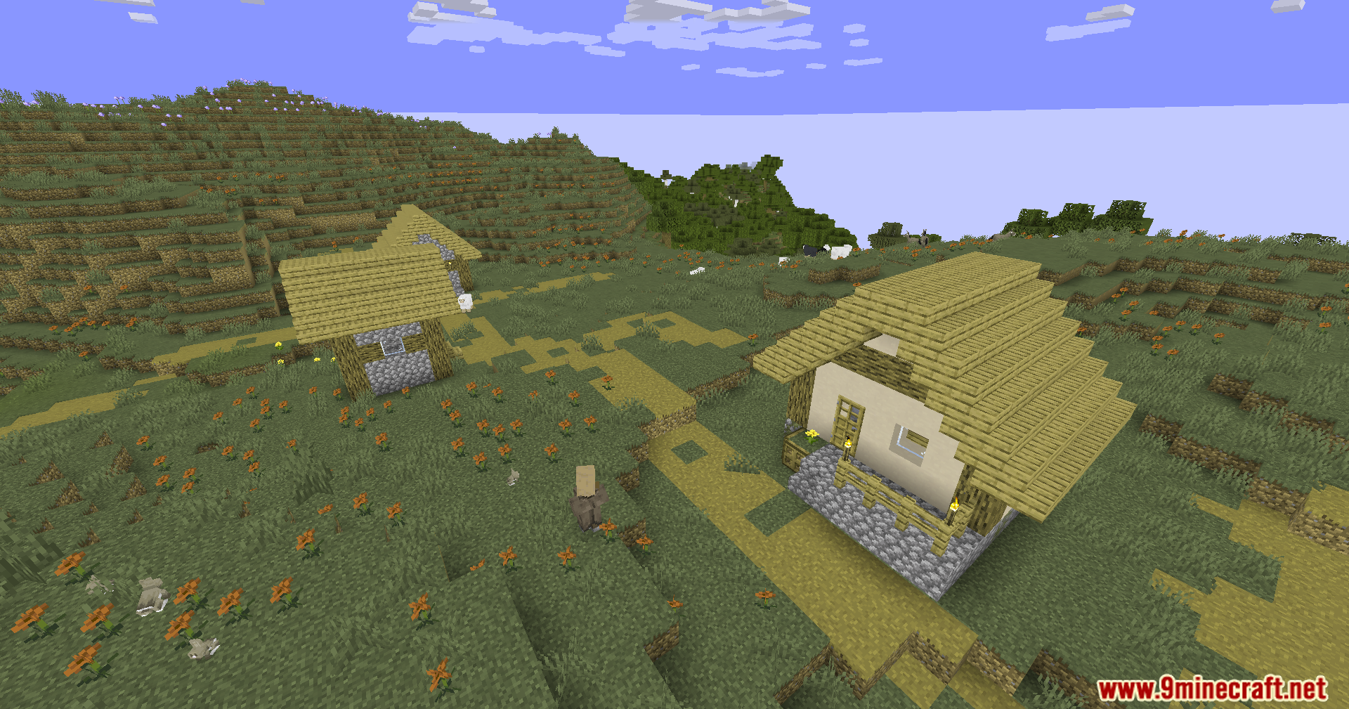 A village scene with two houses and orange flowers under a blue sky