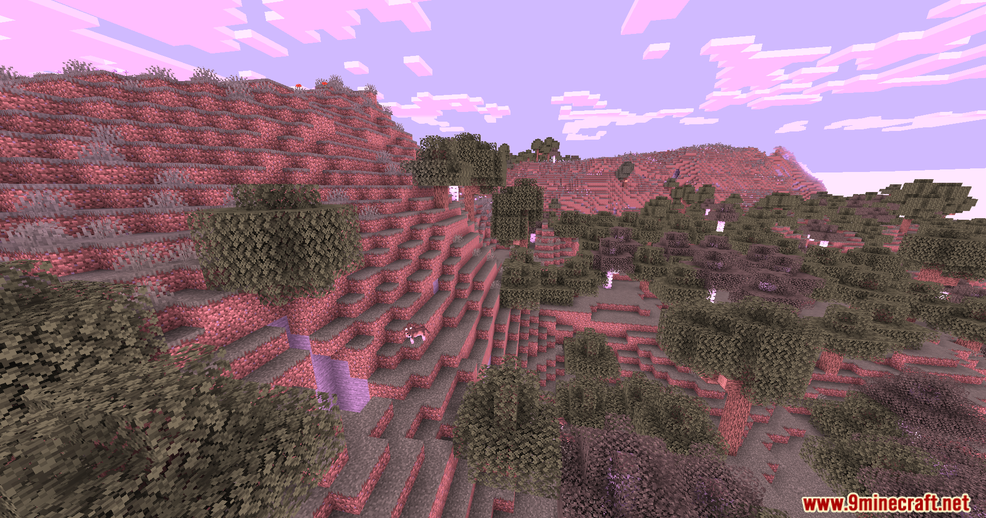 Lush pink forests and hills stretching under a bright purple and pink sky