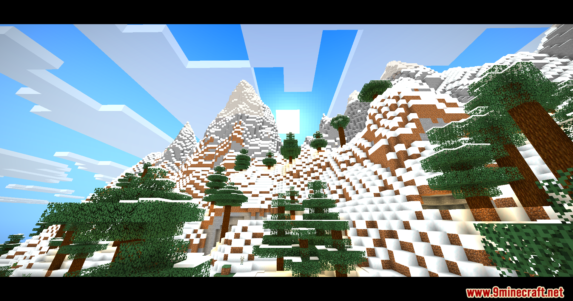 Snowy mountain peaks and pine trees under a bright sky with cinematic bars