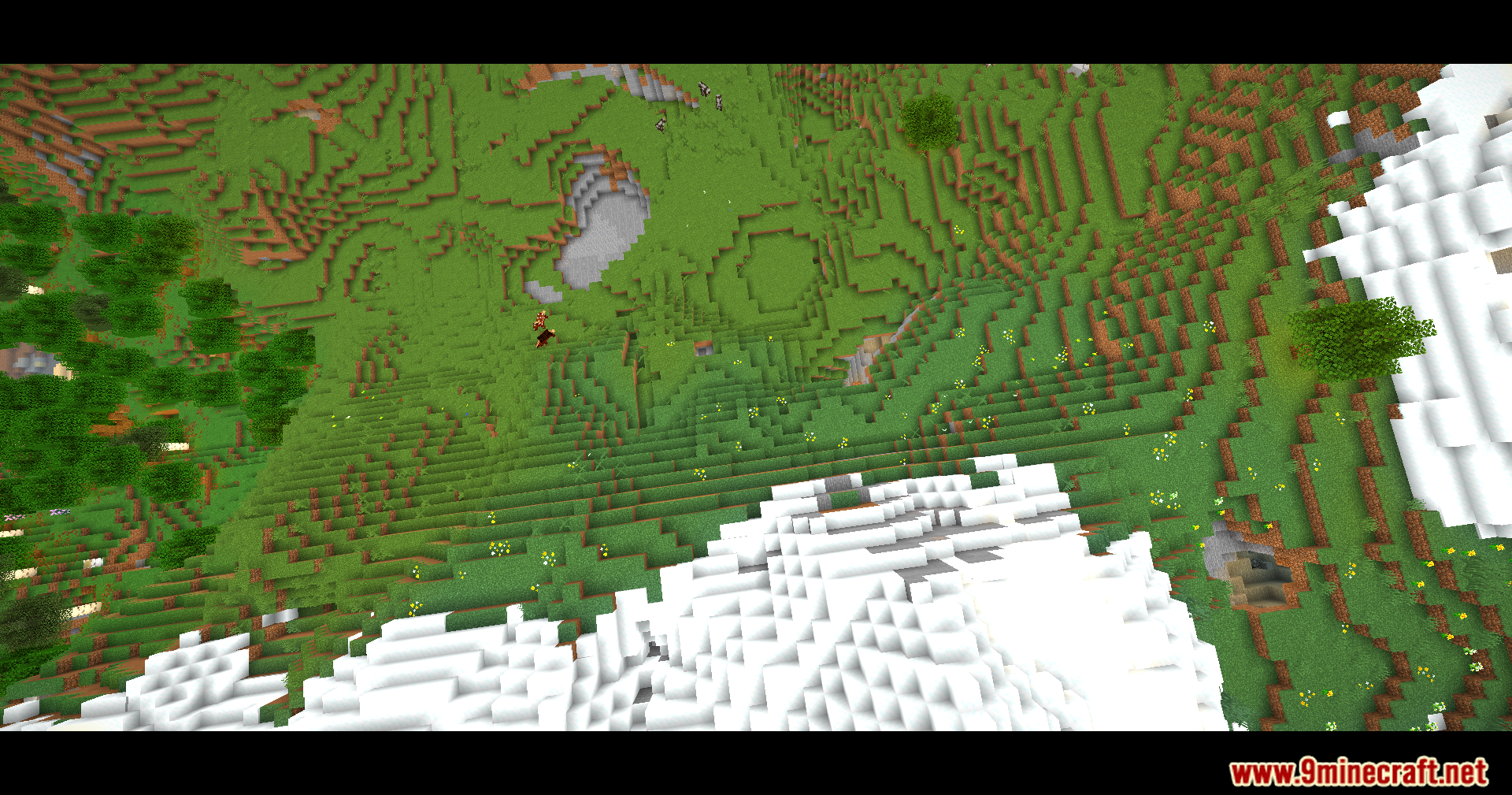 Top down view of a green valley and snowy hills with cinematic bars