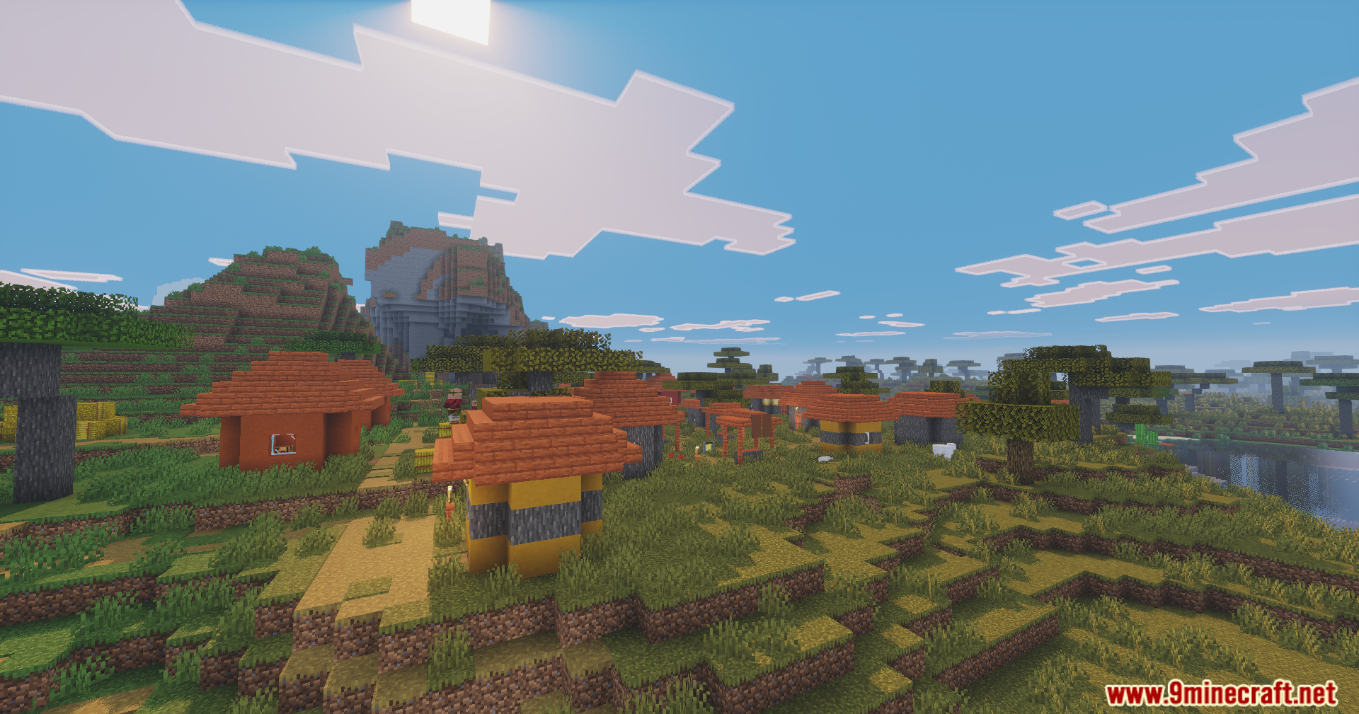 Savanna village with orange roofs and mountains under a clear blue sky