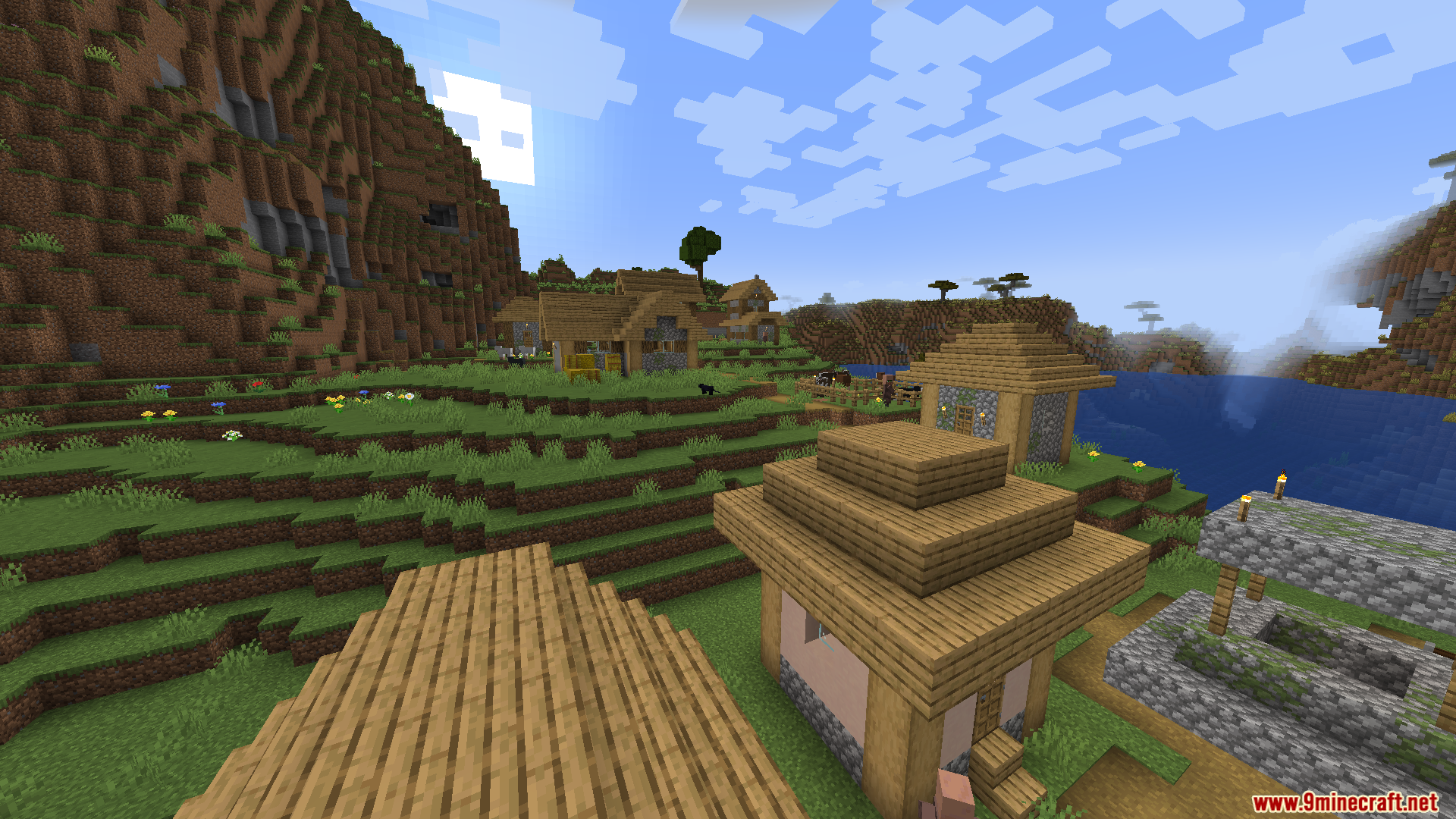 Enough Visuals Mod Screenshot 5 A peaceful Minecraft village with wooden houses near a large mountain and lake