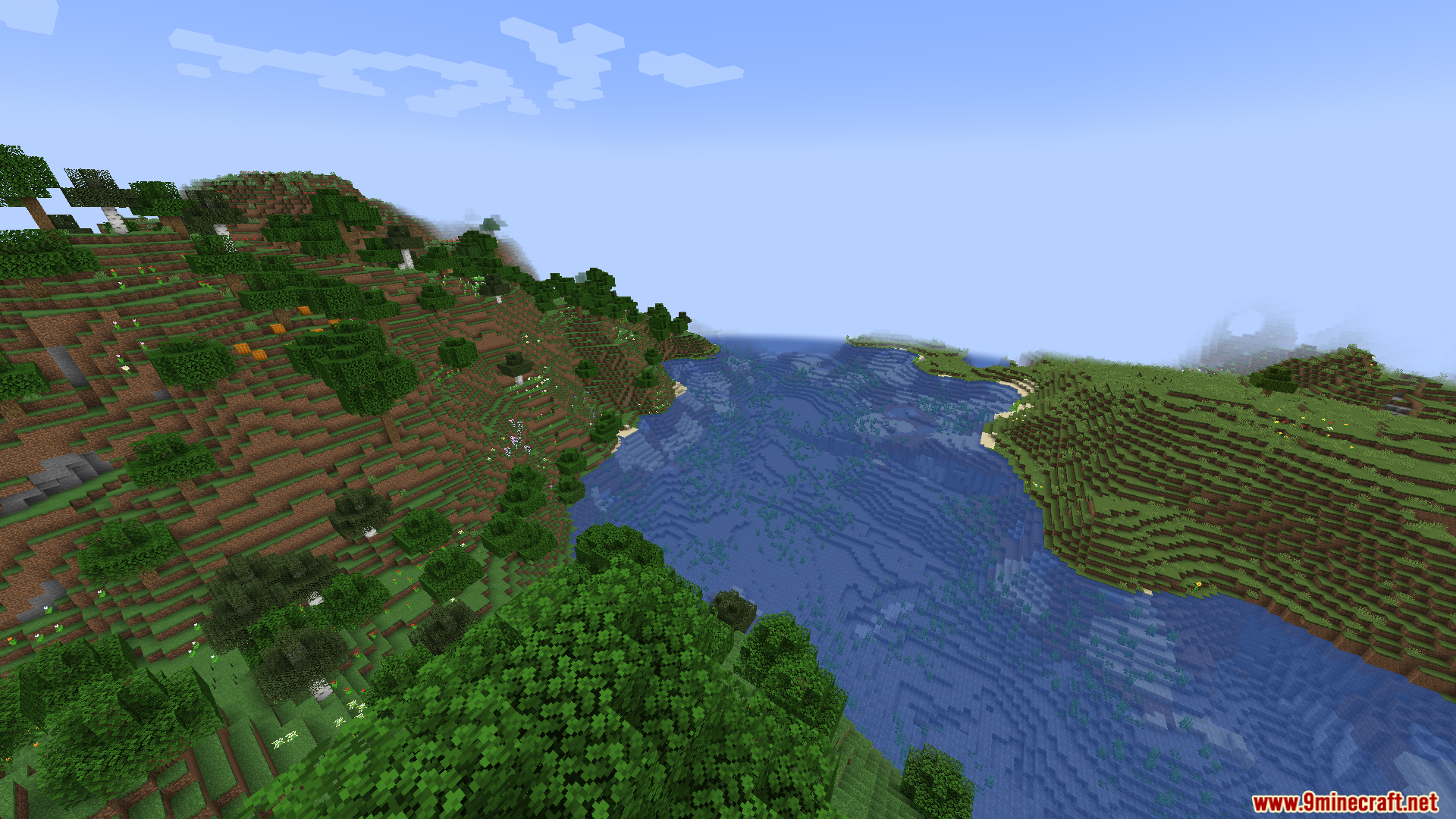 A wide blue river flowing between grassy hills in a Minecraft world