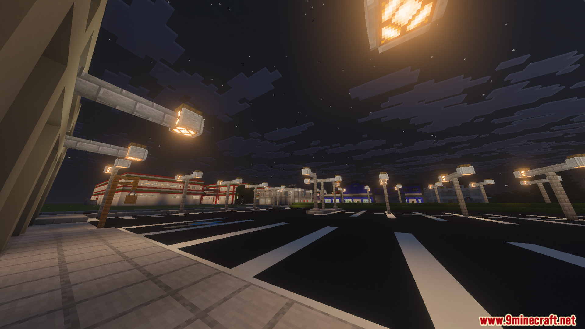 Large parking lot at night with streetlights and buildings in the distance