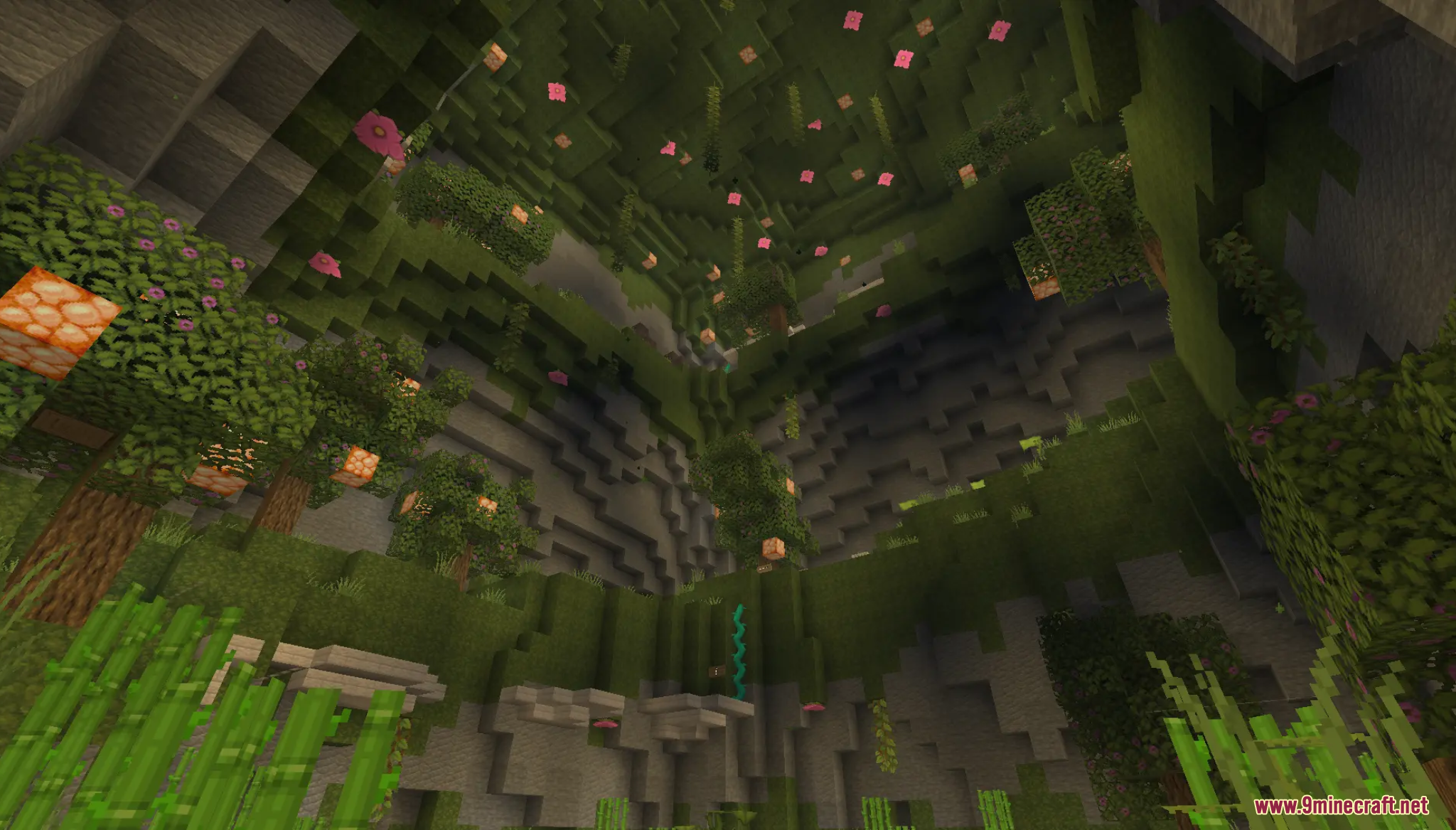 A beautiful lush cave filled with green trees and hanging pink flowers