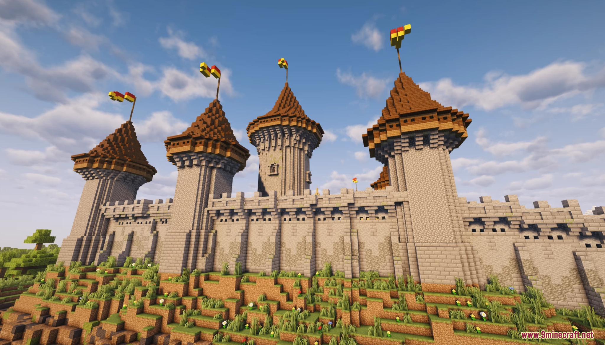 Close up of stone castle towers with flags on a grassy hill