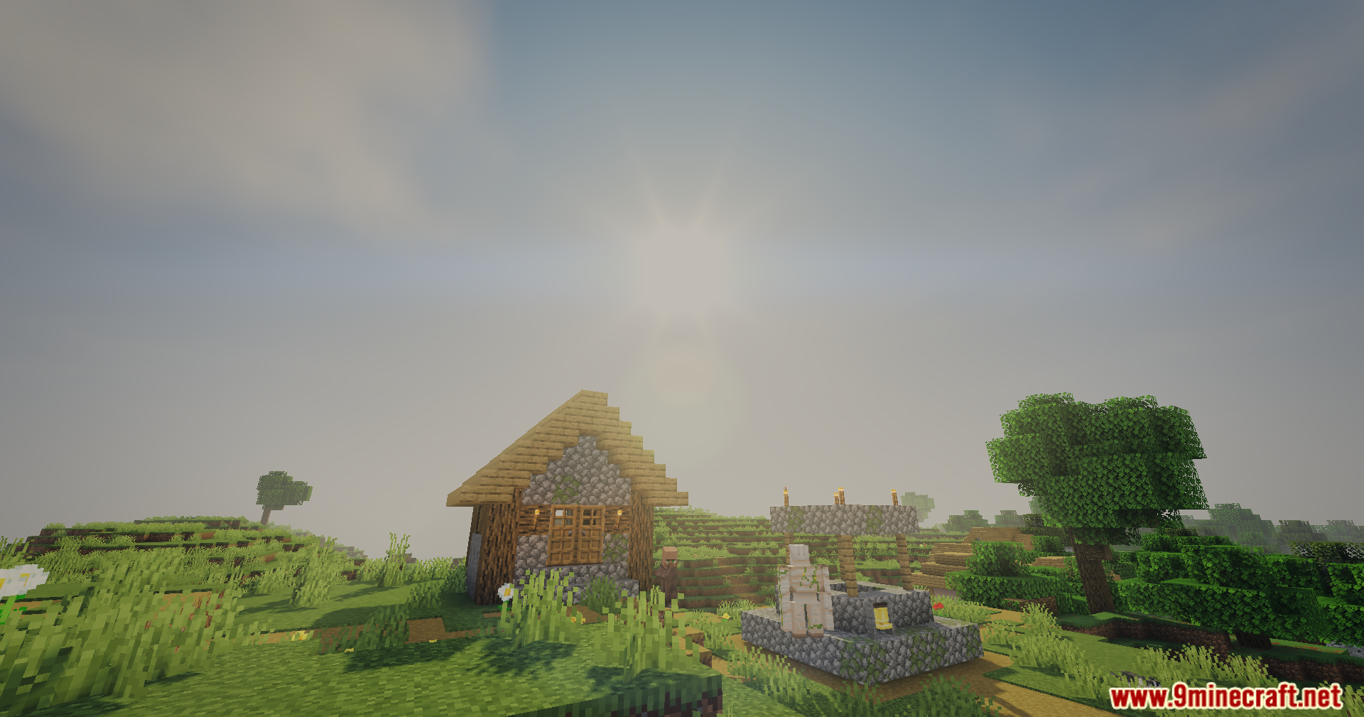 A small village house and iron golem stand near a well under sunlight