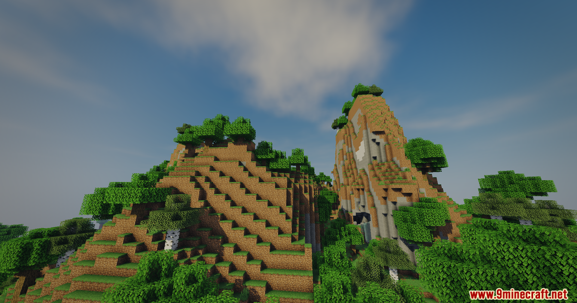 A scenic view of tall grassy hills and lush green trees under clouds
