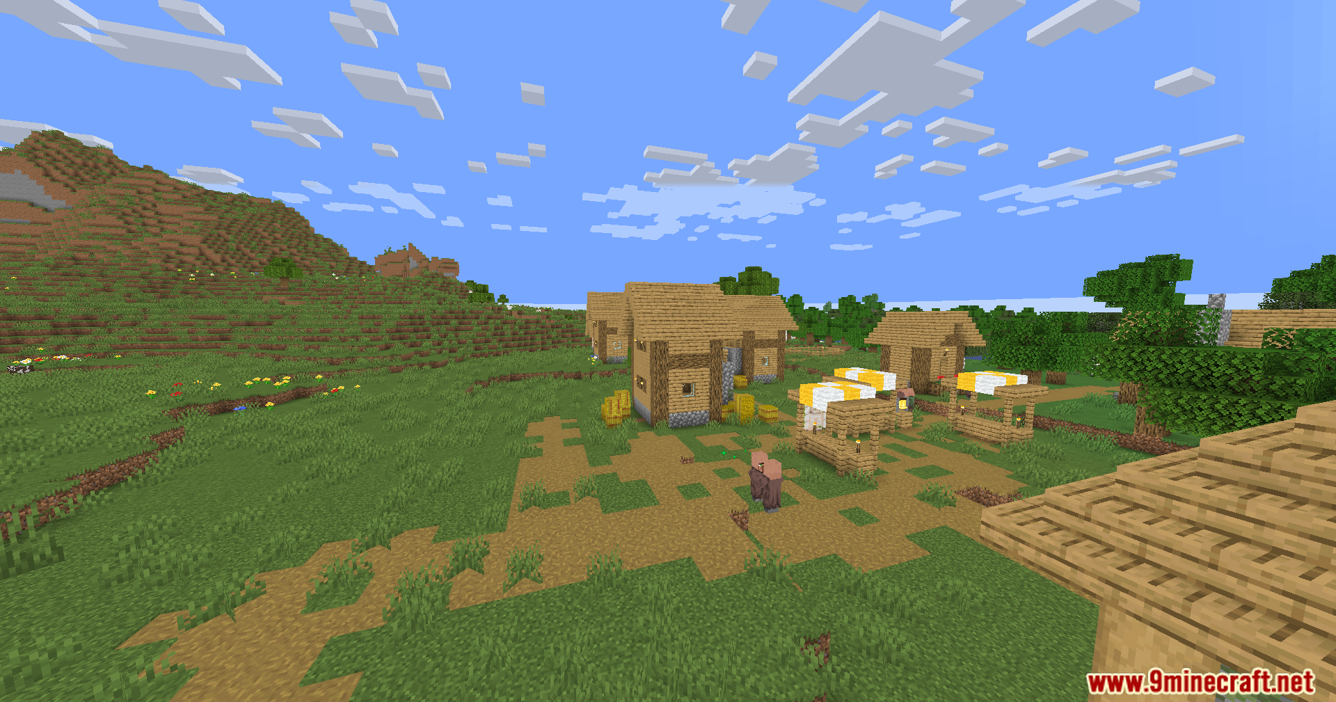 Two villagers stand near market stalls and wooden houses in a sunny village